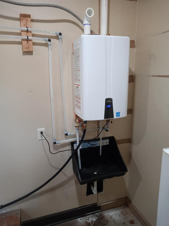 A white water heater is hanging on a wall next to a sink.
