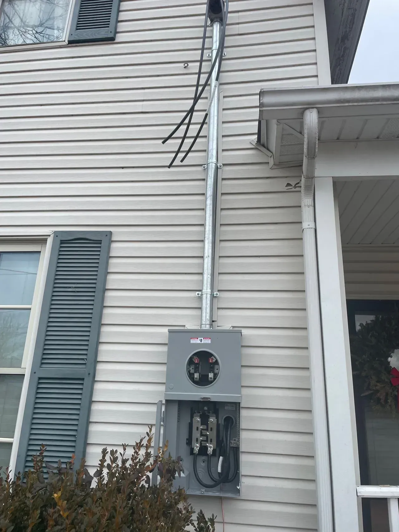 An electrical box is attached to the side of a house.