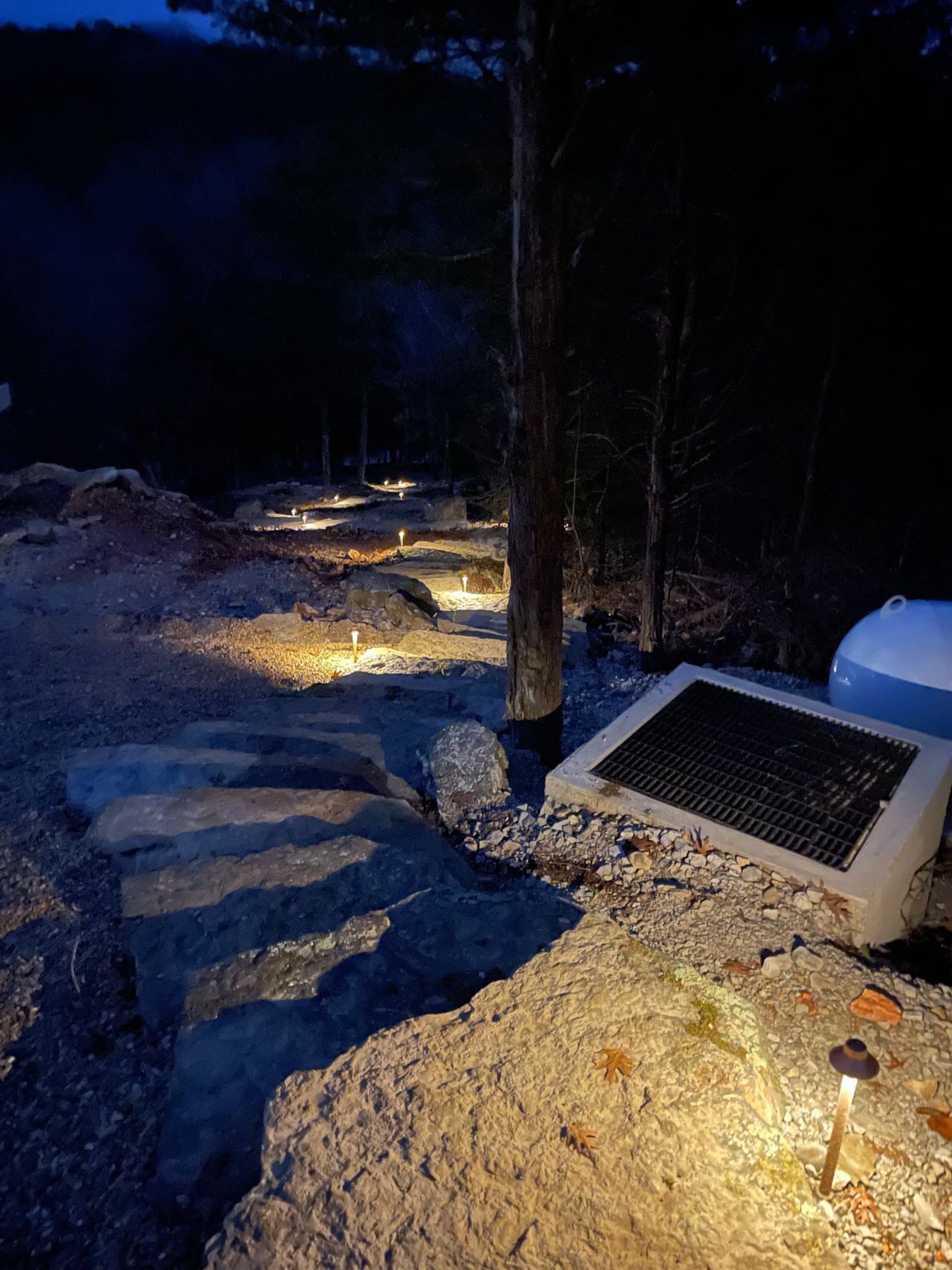 A solar panel is sitting on top of a rocky hillside at night.