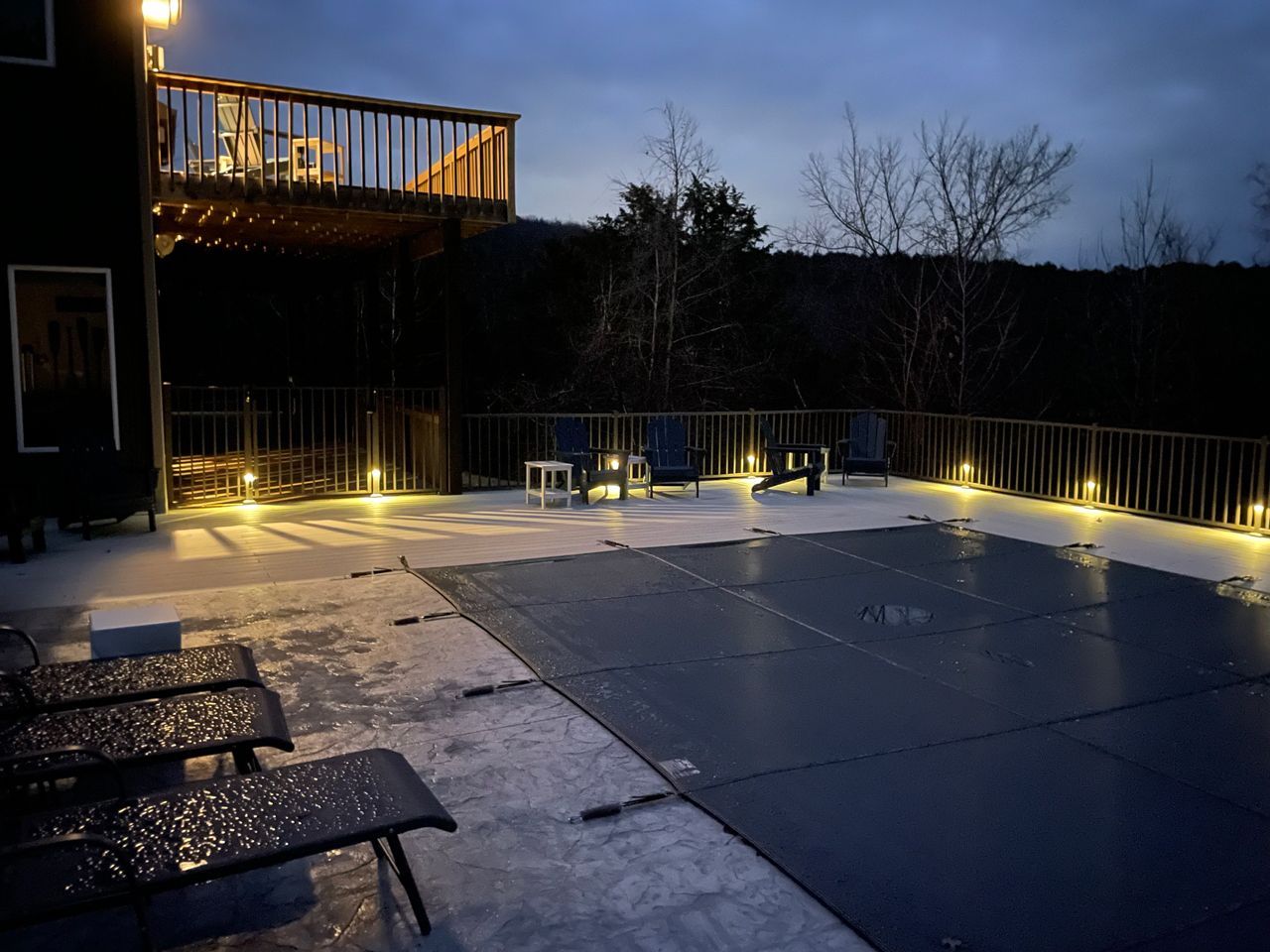 A swimming pool is covered in snow and lit up at night.