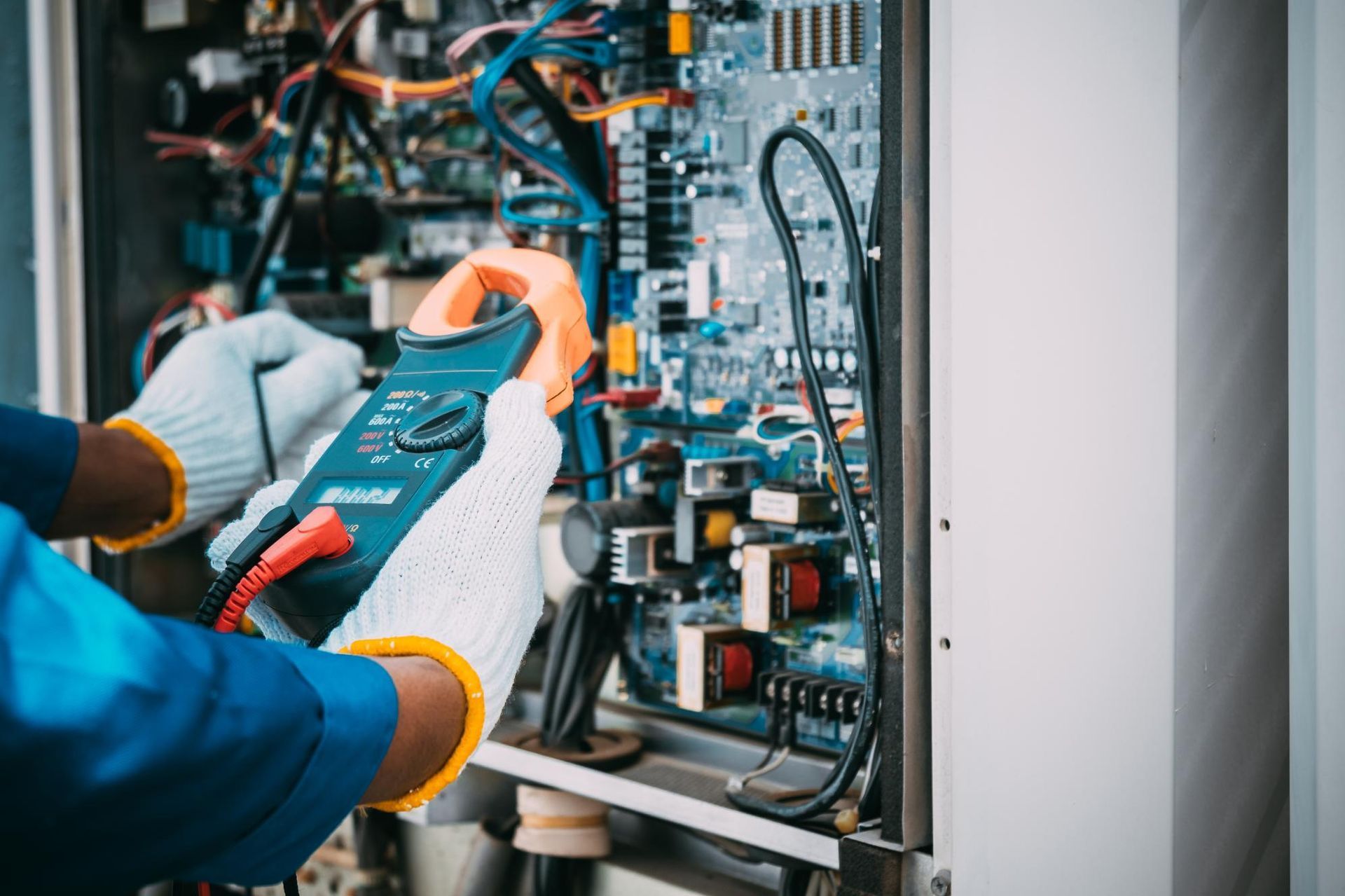 An electrician is working on a machine with a multimeter.