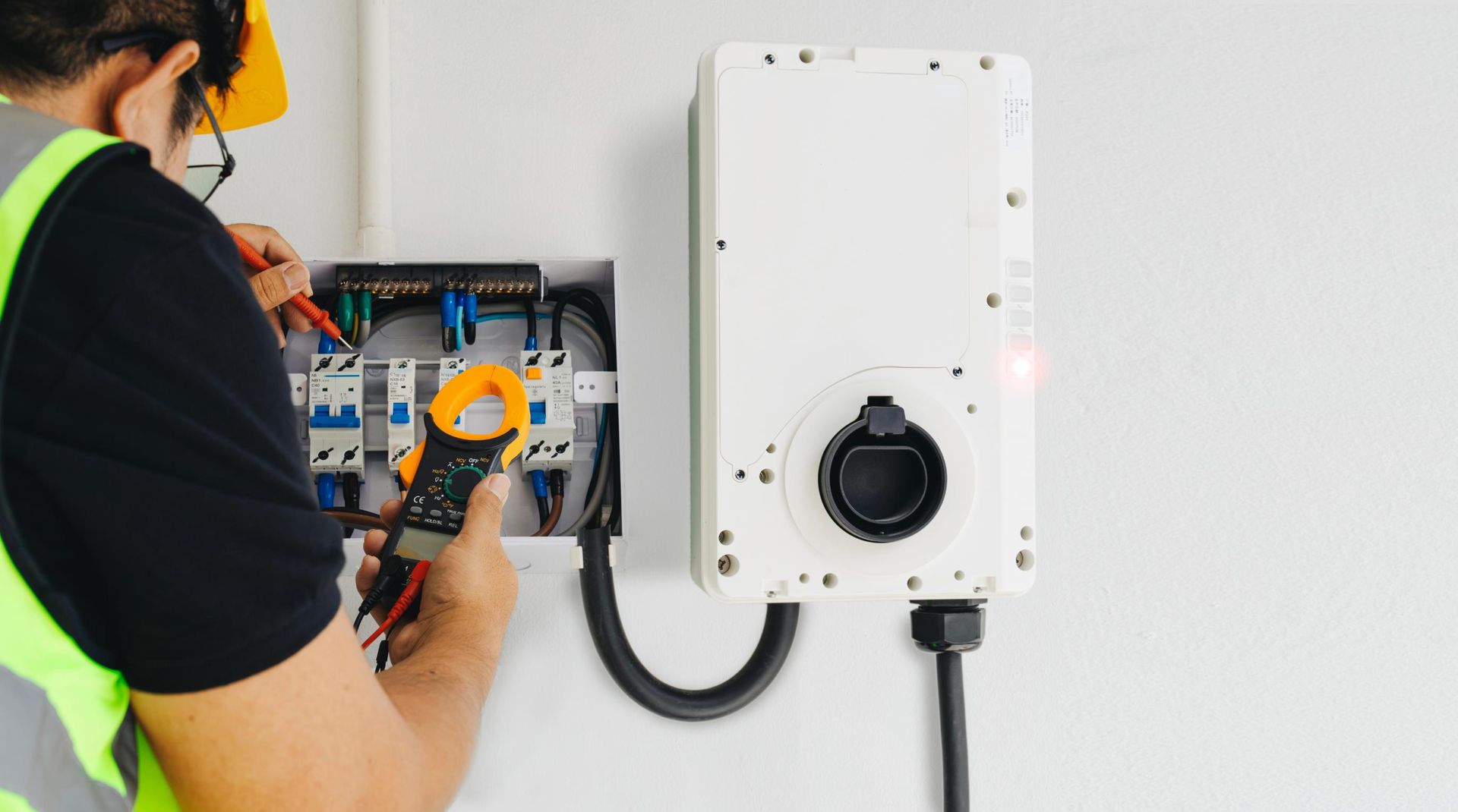 A man is working on an electric car charger on a wall.