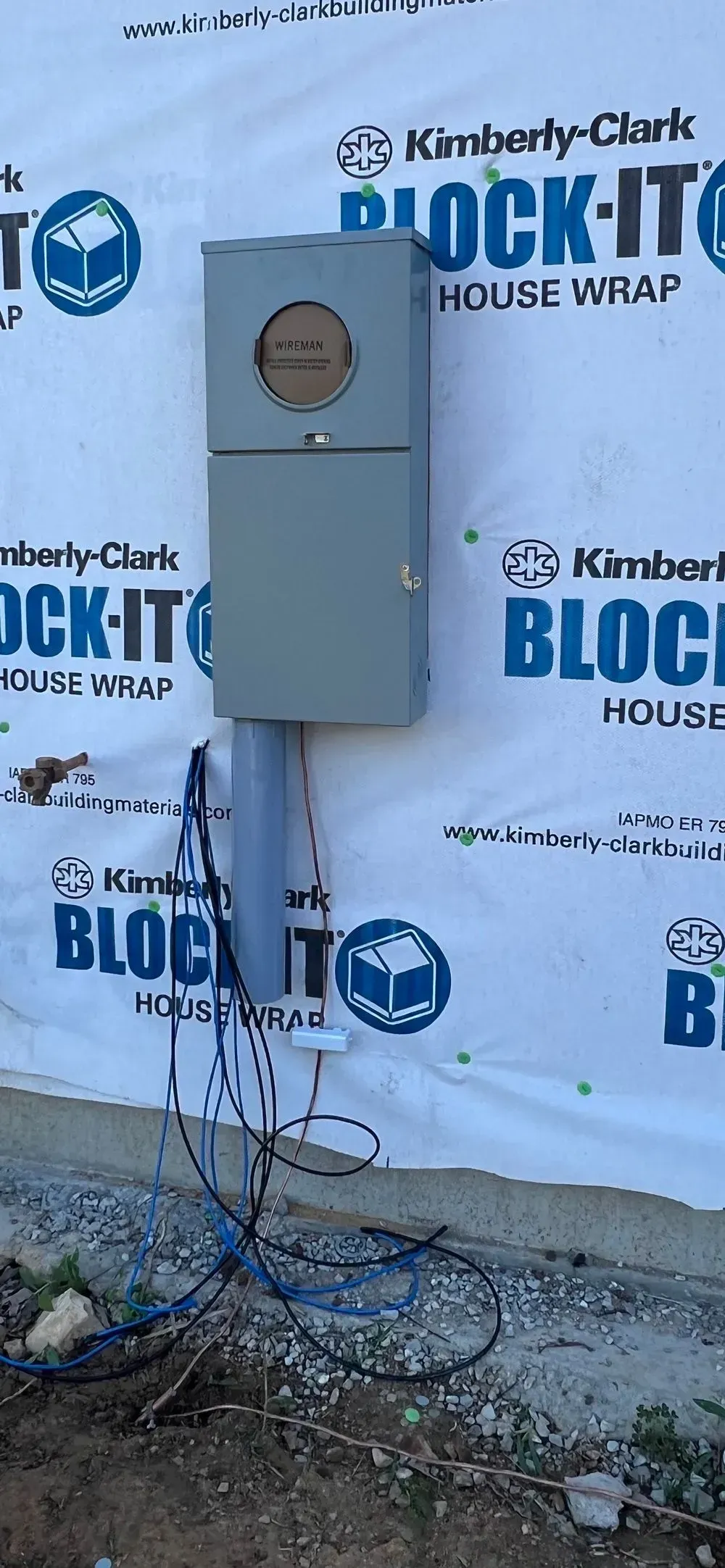 A electrical box is sitting on the side of a building.