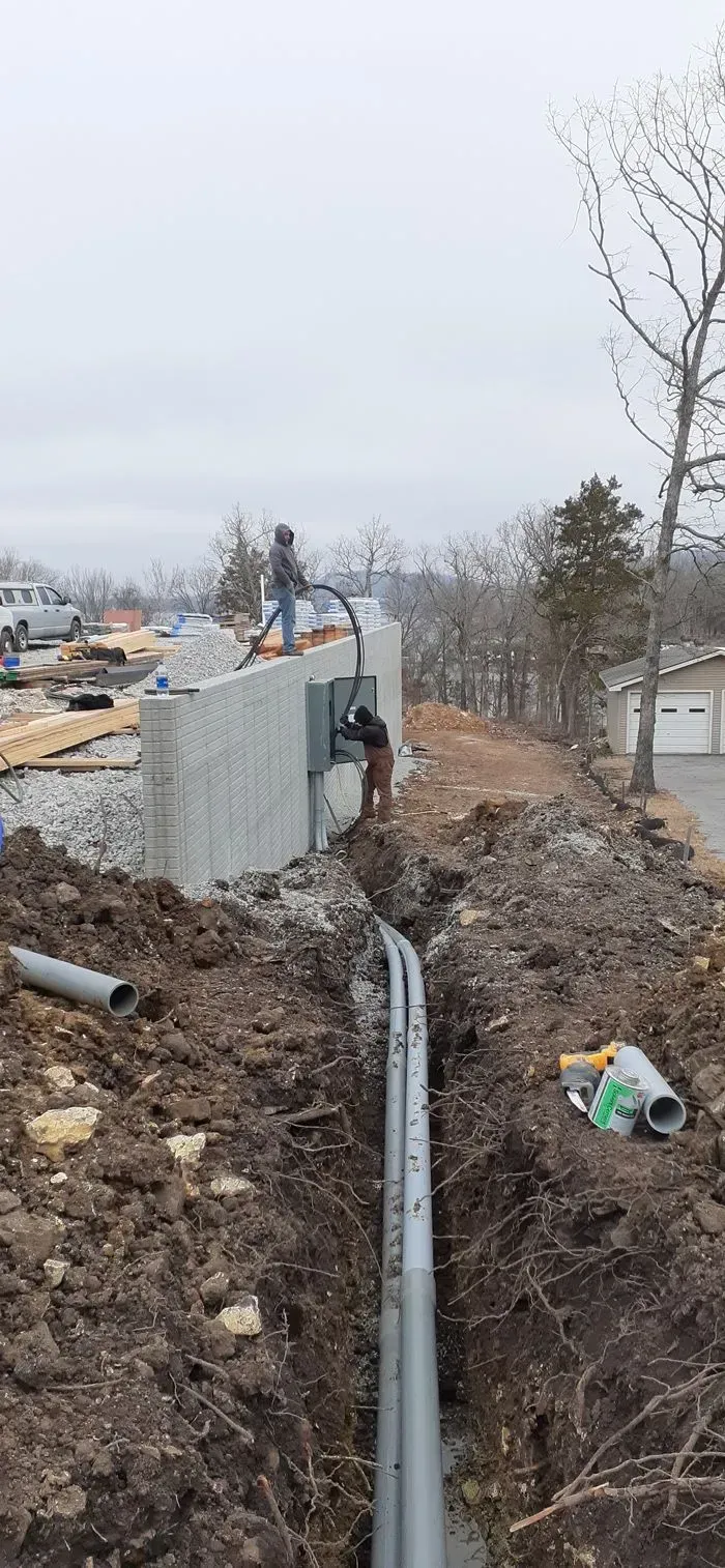 A man is working on a pipe in a trench.