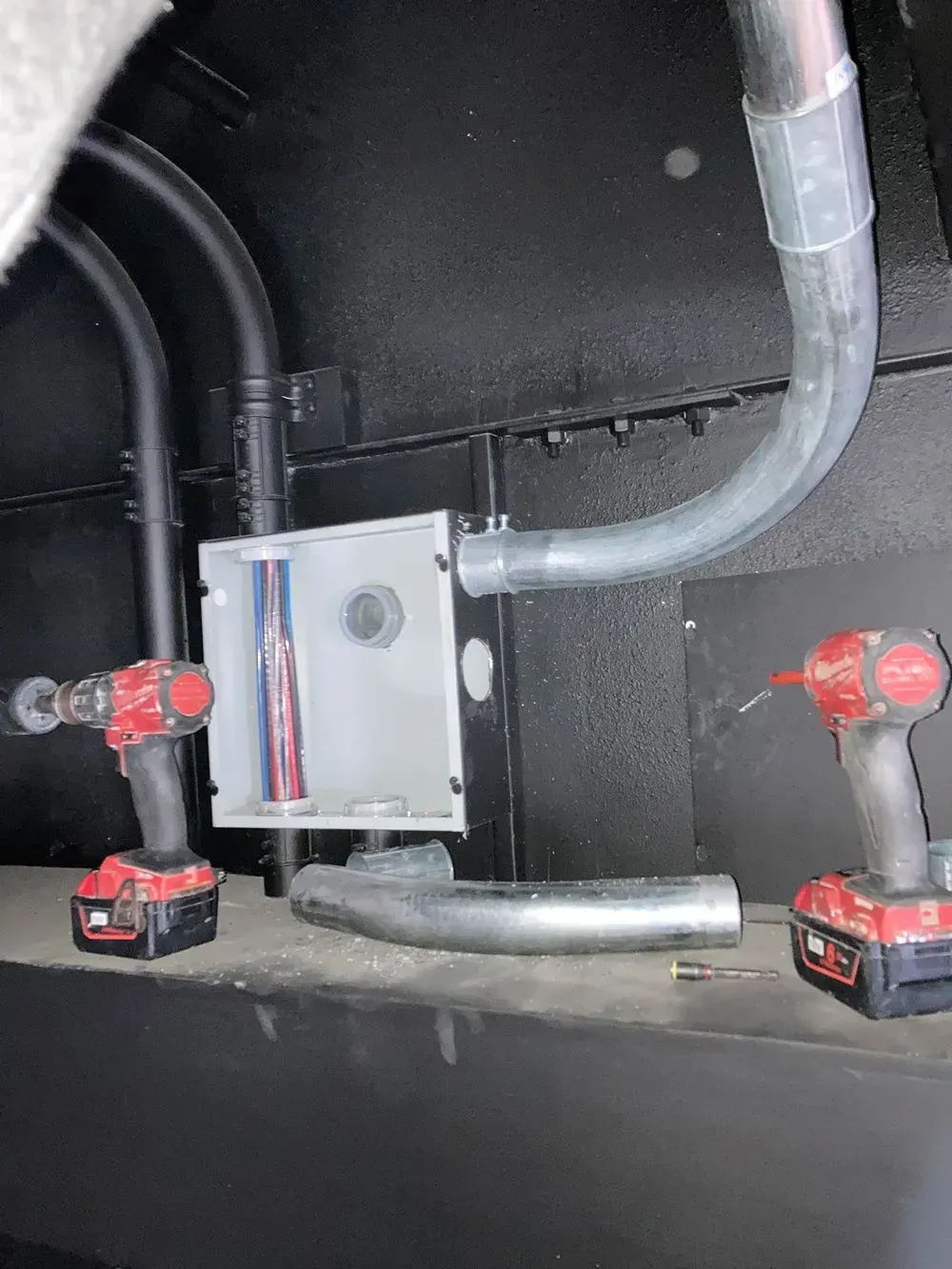 Two cordless drills are sitting next to each other on a wall.