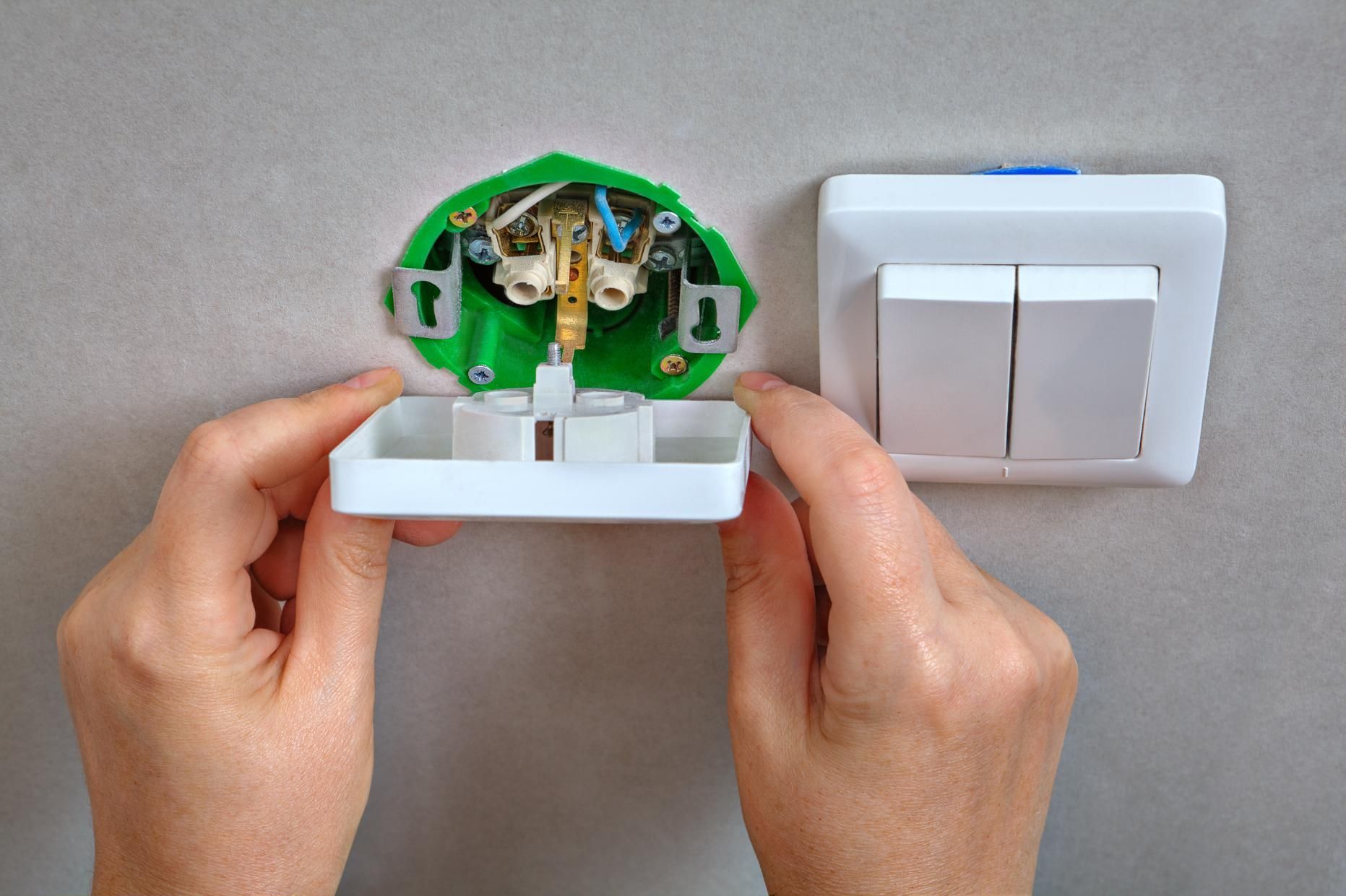A person is installing a light switch on a wall.
