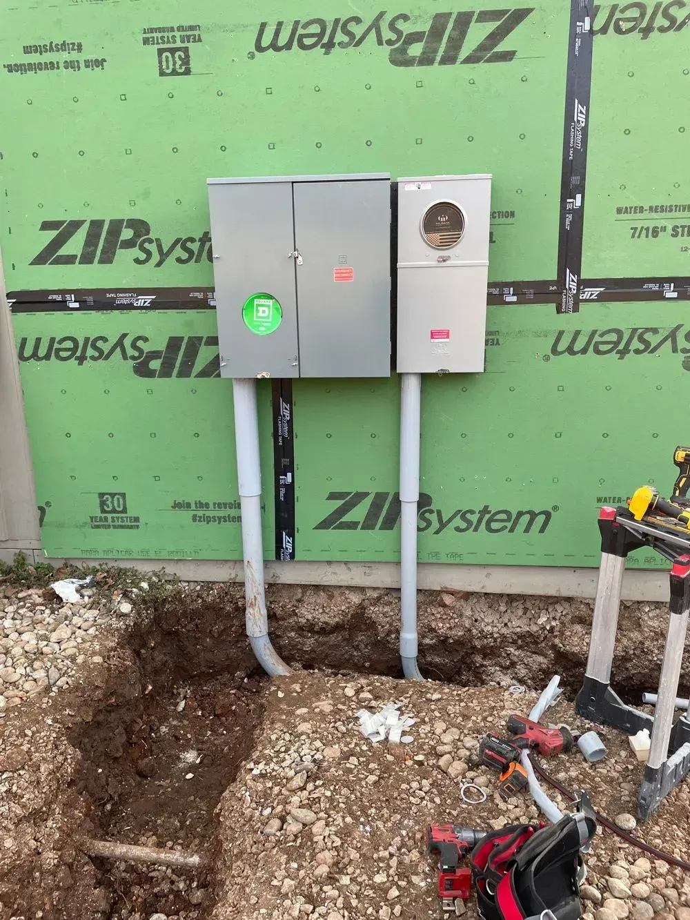 A electrical box is being installed on the side of a building.