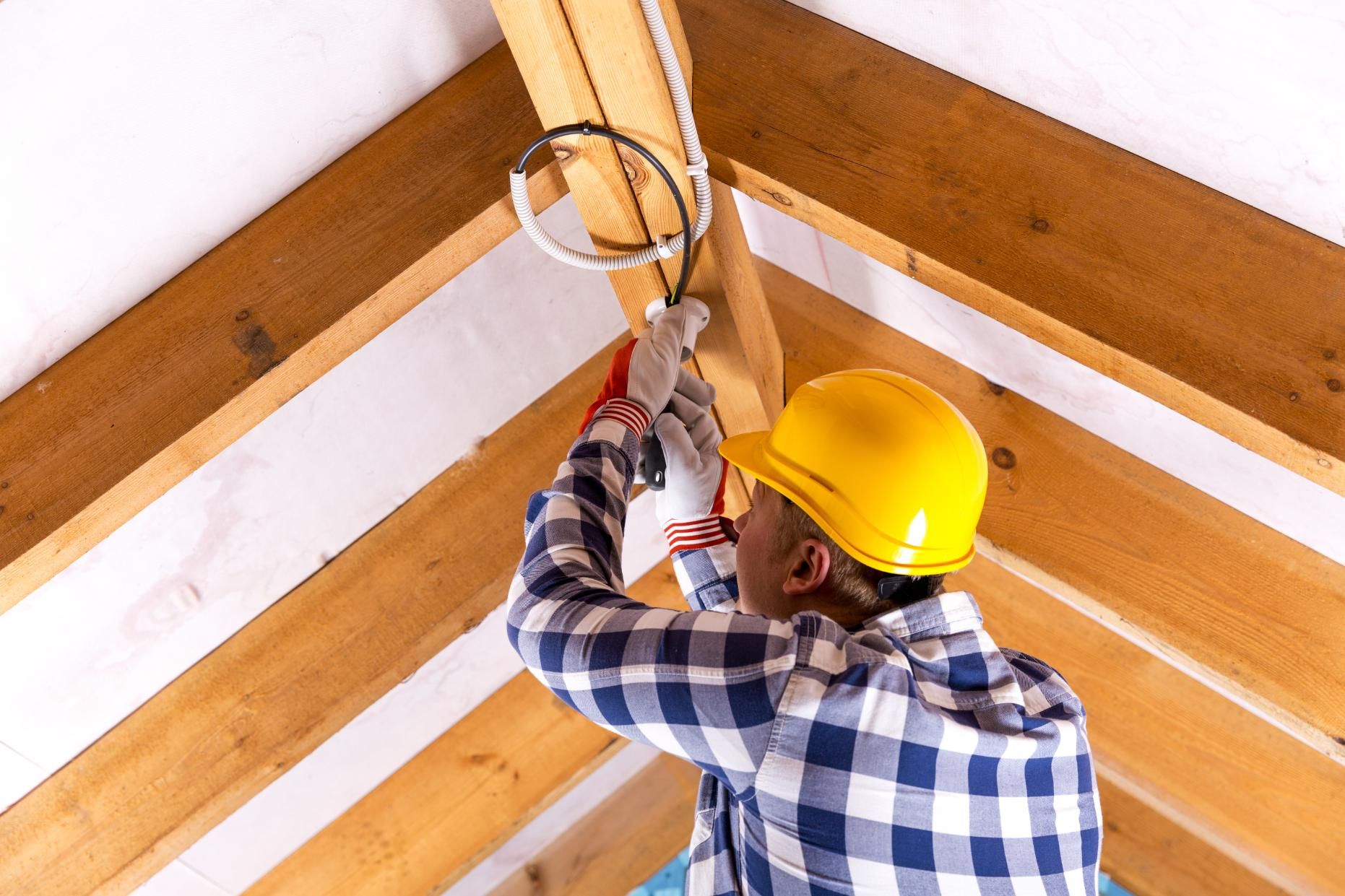 A man in a hard hat is working on a wooden ceiling.