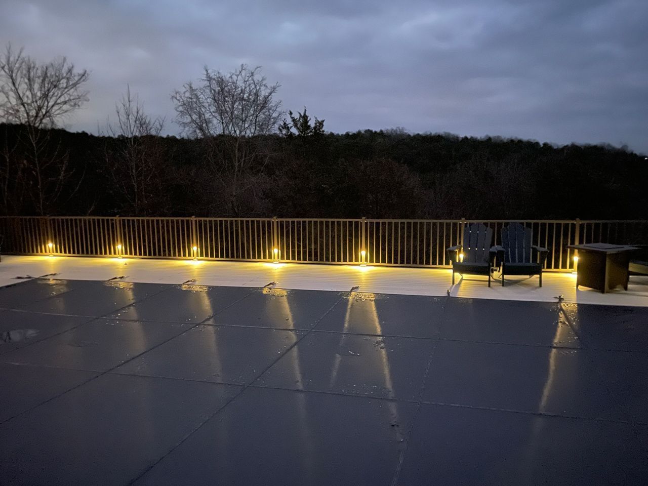 A patio with chairs and a table with lights on it at night.