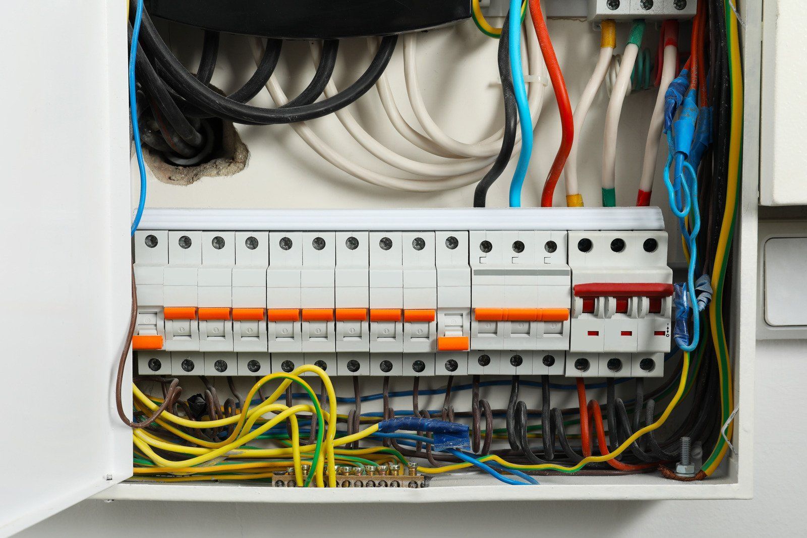 Open electrical panel with circuit breakers and wires.