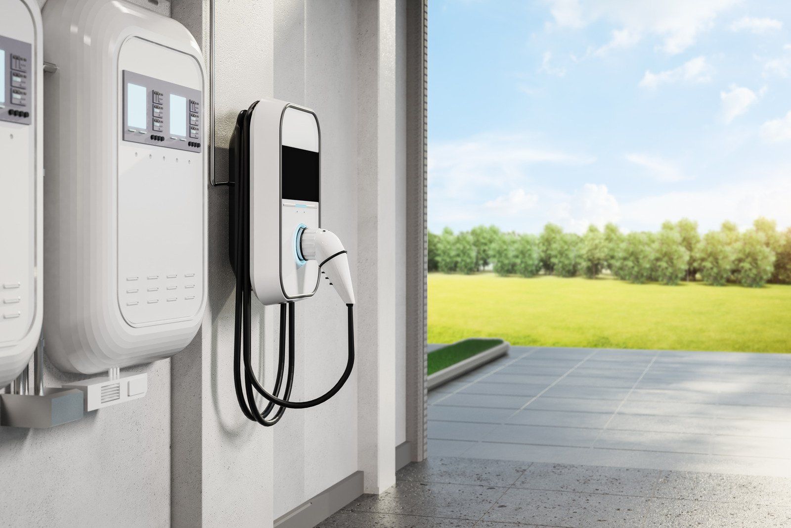 Wall-mounted electric vehicle charger with a charging cable plugged in. The background shows a sunny outdoor scene.
