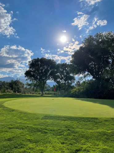 A golf course with the sun shining through the clouds