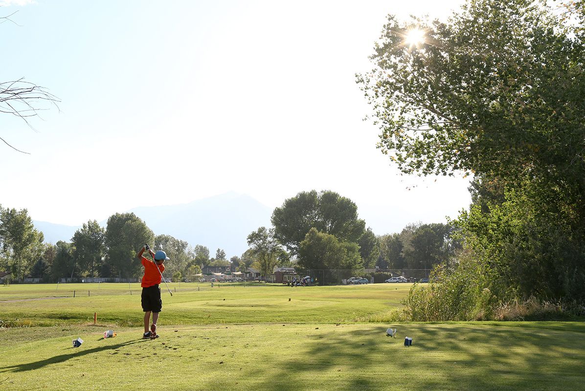 A man is swinging a golf club on a golf course.