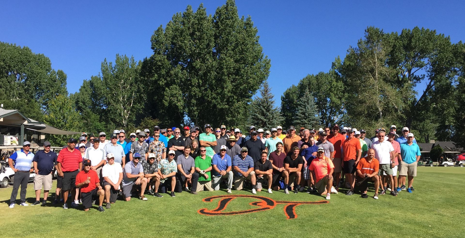 A large group of people are posing for a picture on a golf course.
