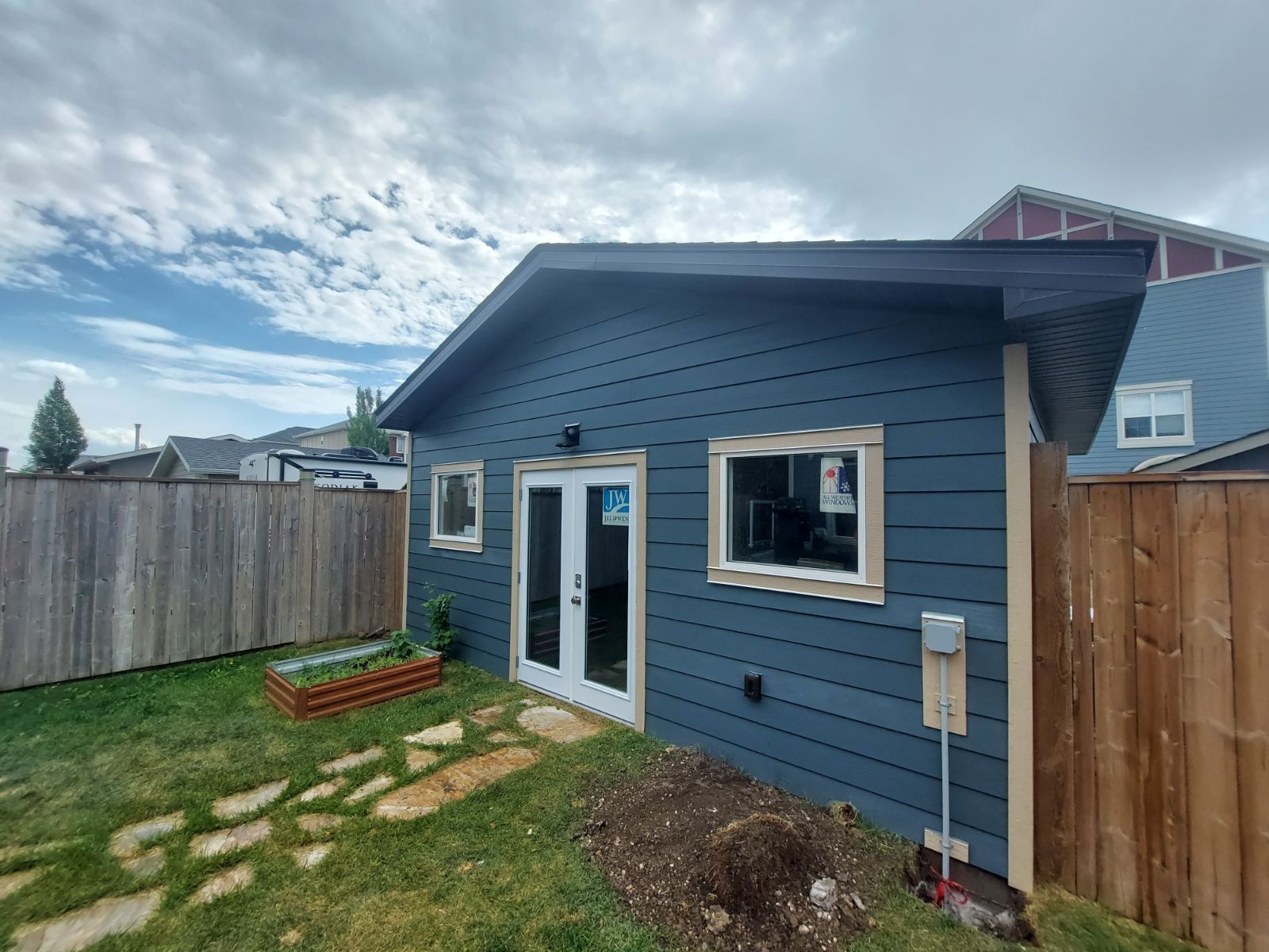 A small blue house with a wooden fence in the backyard.