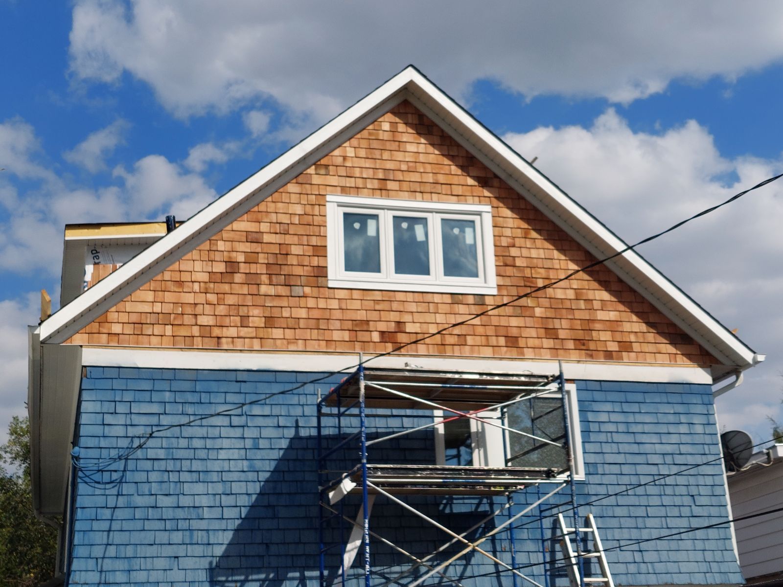 A blue and brown house with a scaffolding in front of it.
