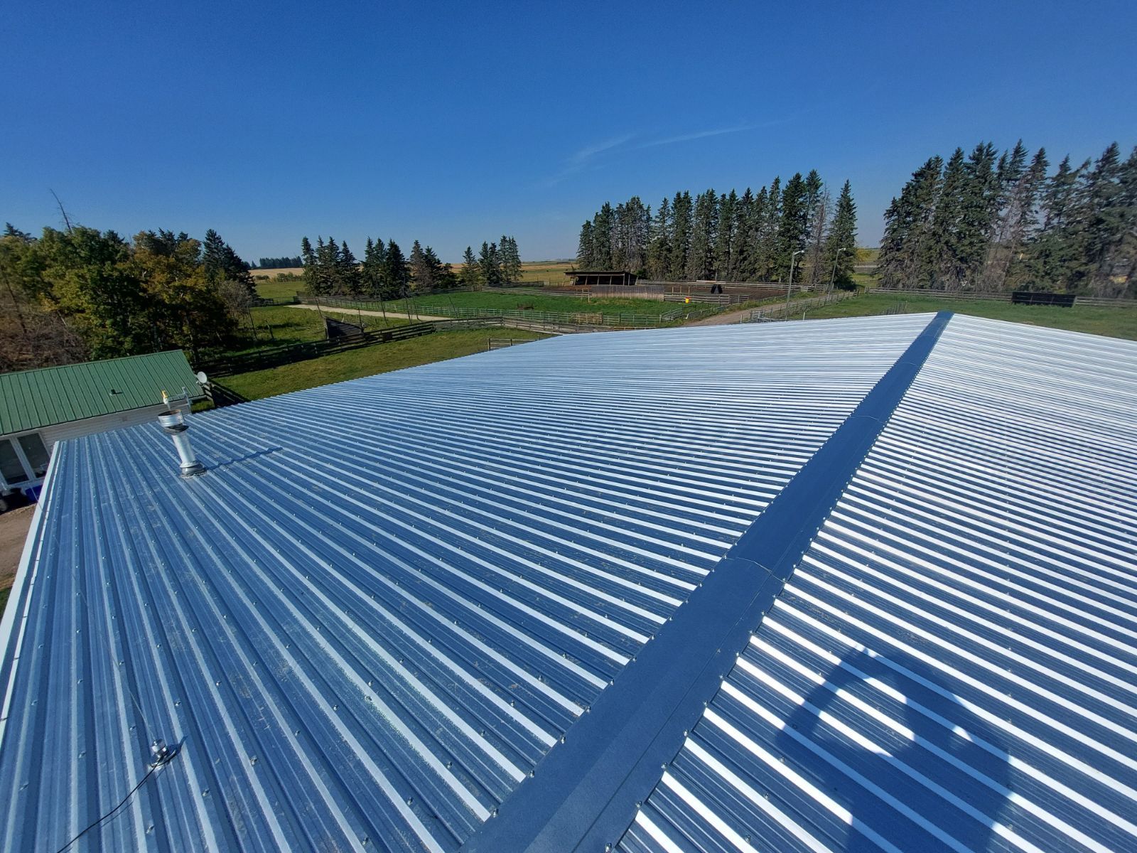 A large metal roof with trees in the background