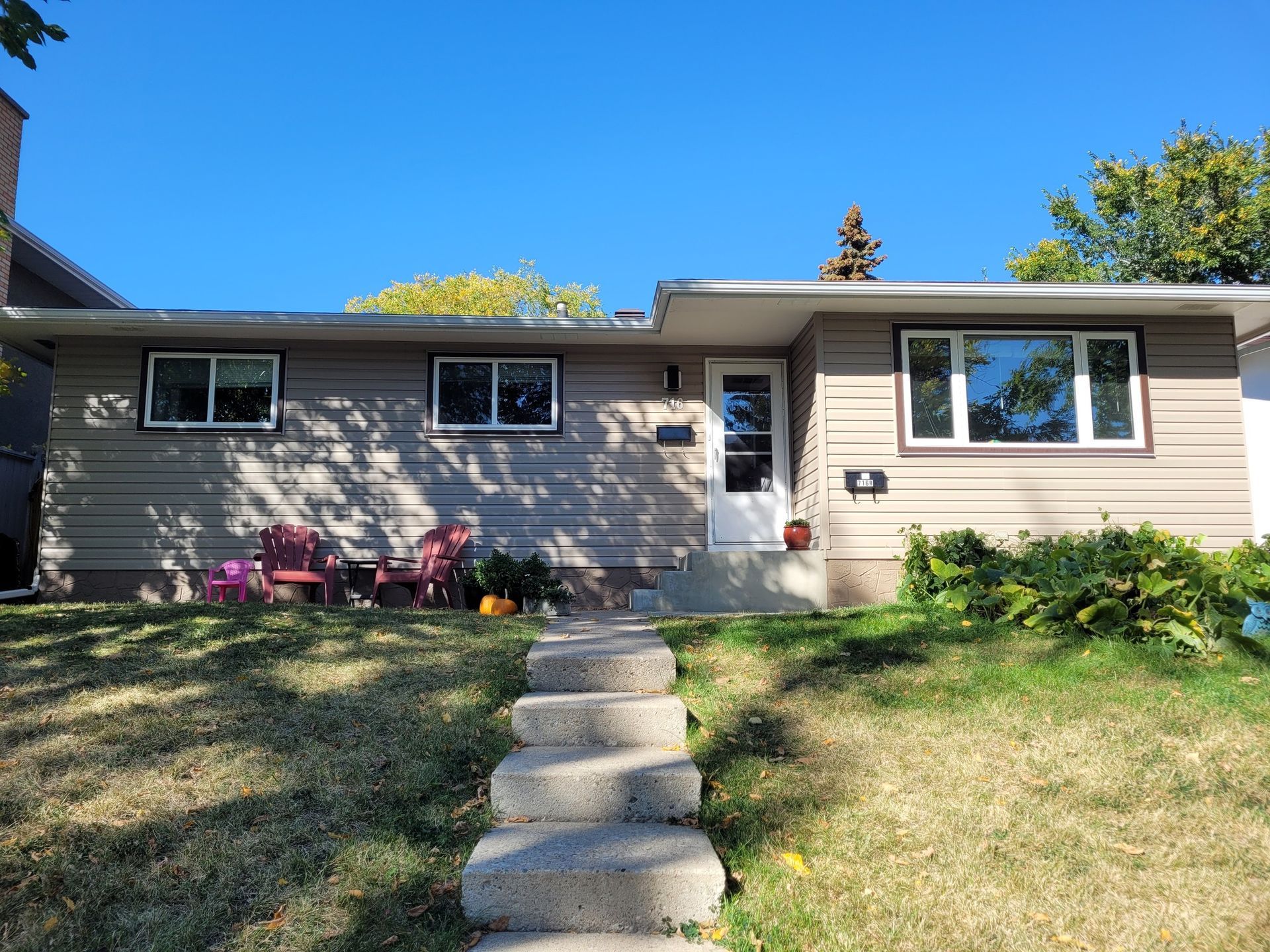 A house with stairs leading up to it and a lawn in front of it.