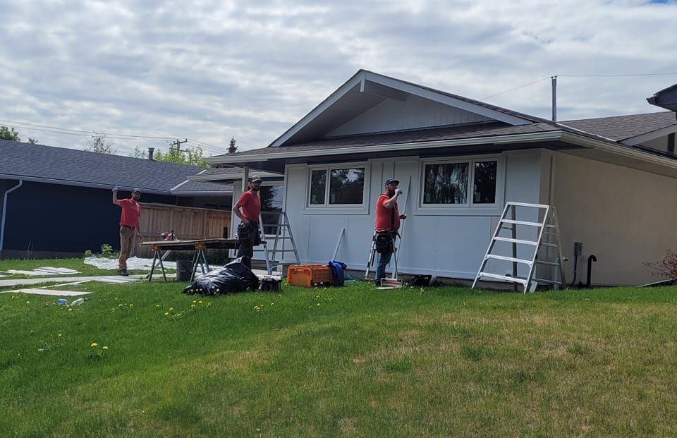 A group of men are painting a white house in a backyard.