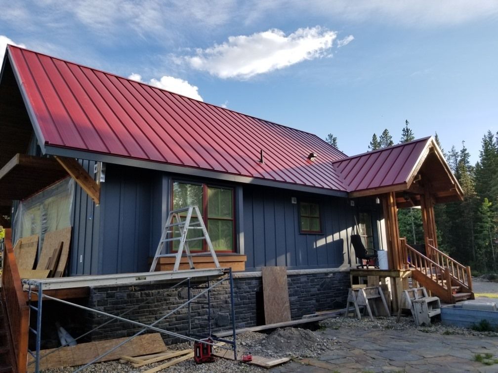A house with a red metal roof is being built.