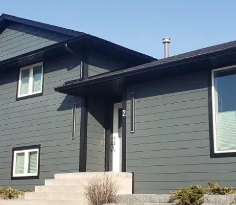 The front of a house with a gray siding and black trim.