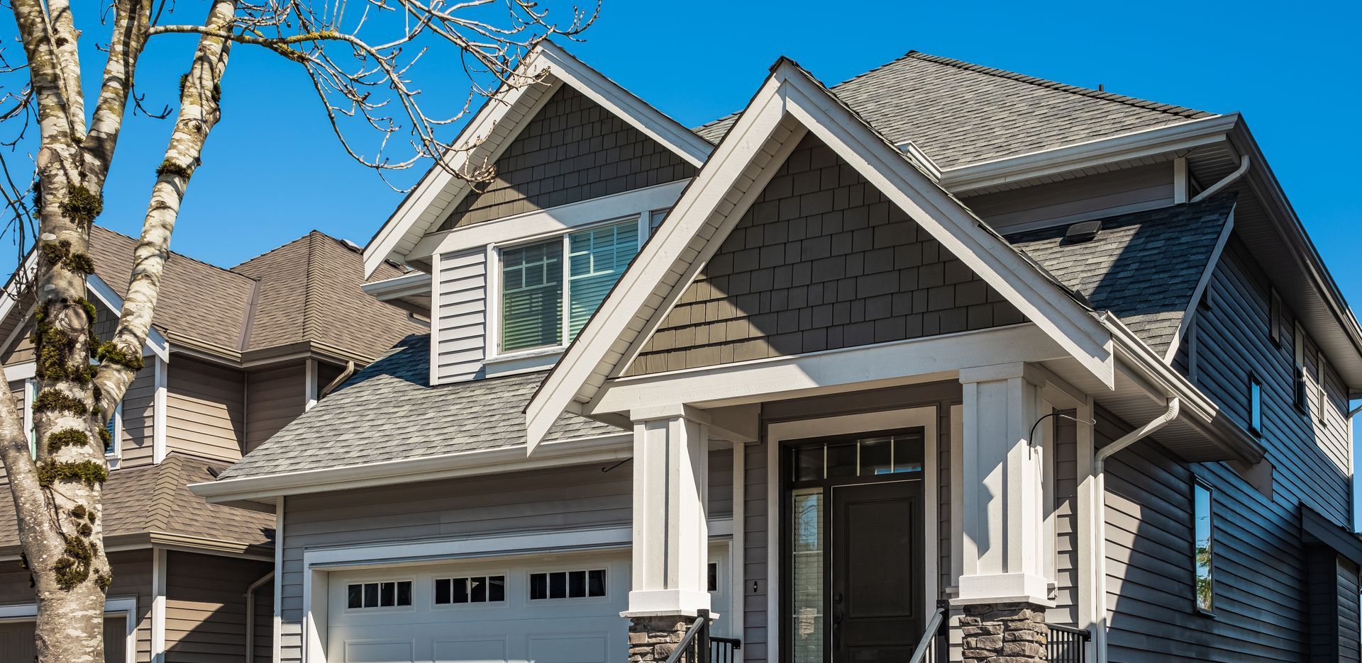 Modern gray house with white trim, blue sky background.
