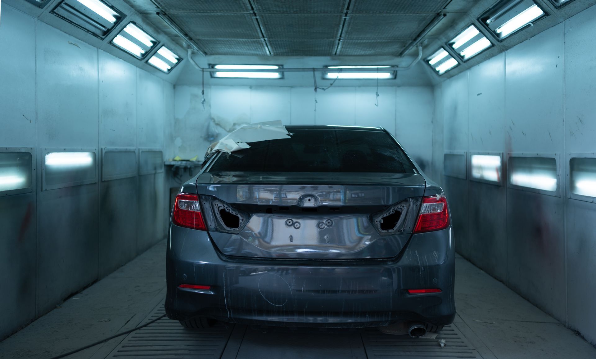 Dark gray sedan parked inside a brightly lit indoor car wash bay