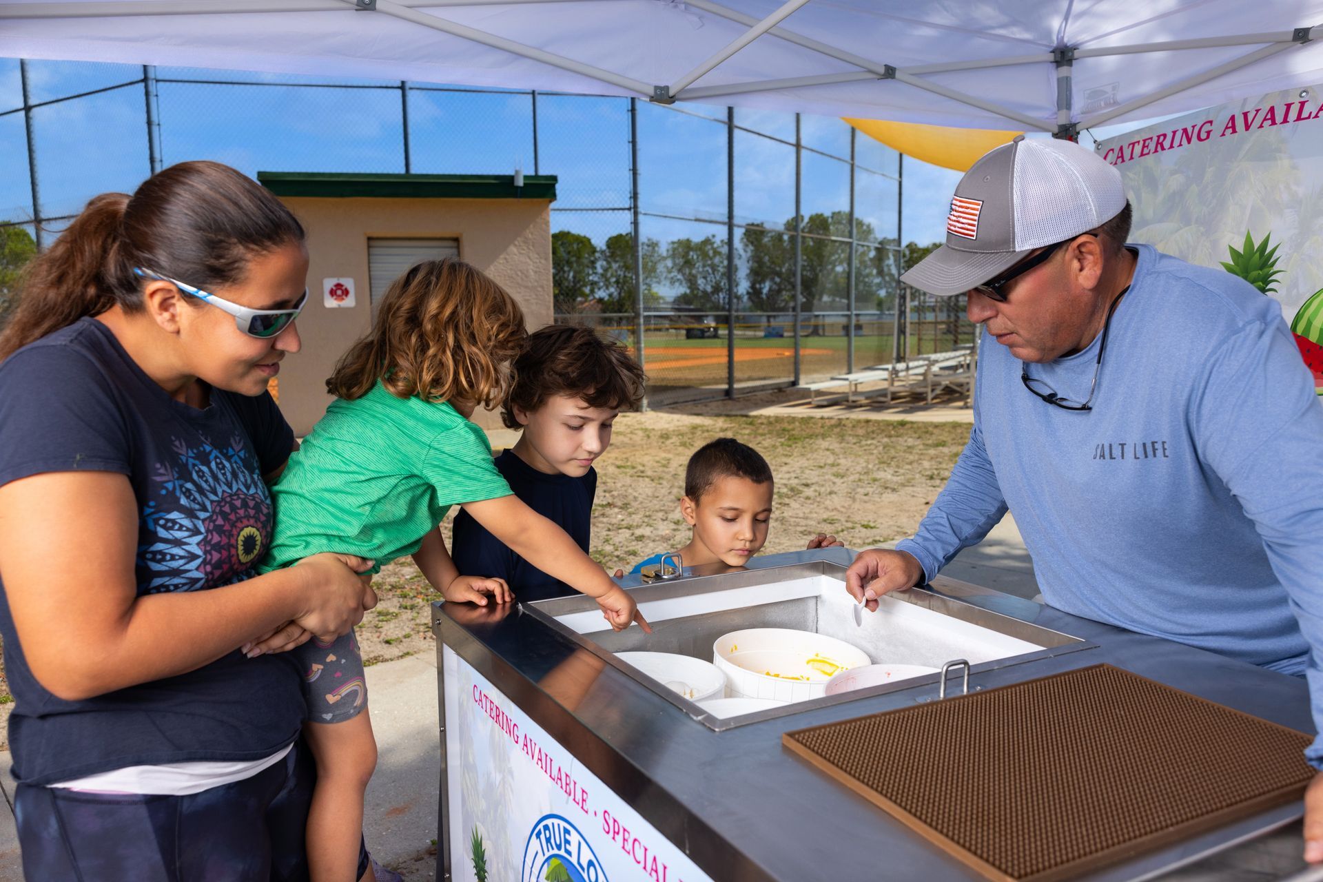 A group of people are standing around a table looking at ice cream.