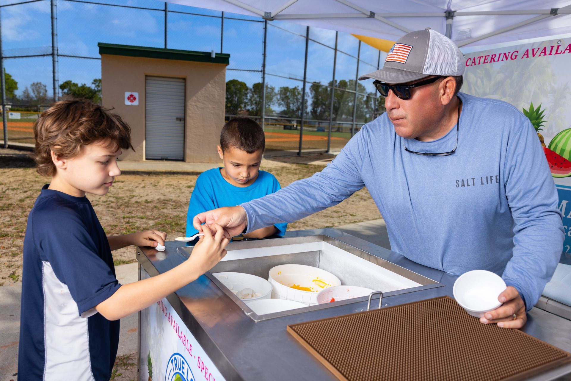 A man is selling ice cream to two young boys.