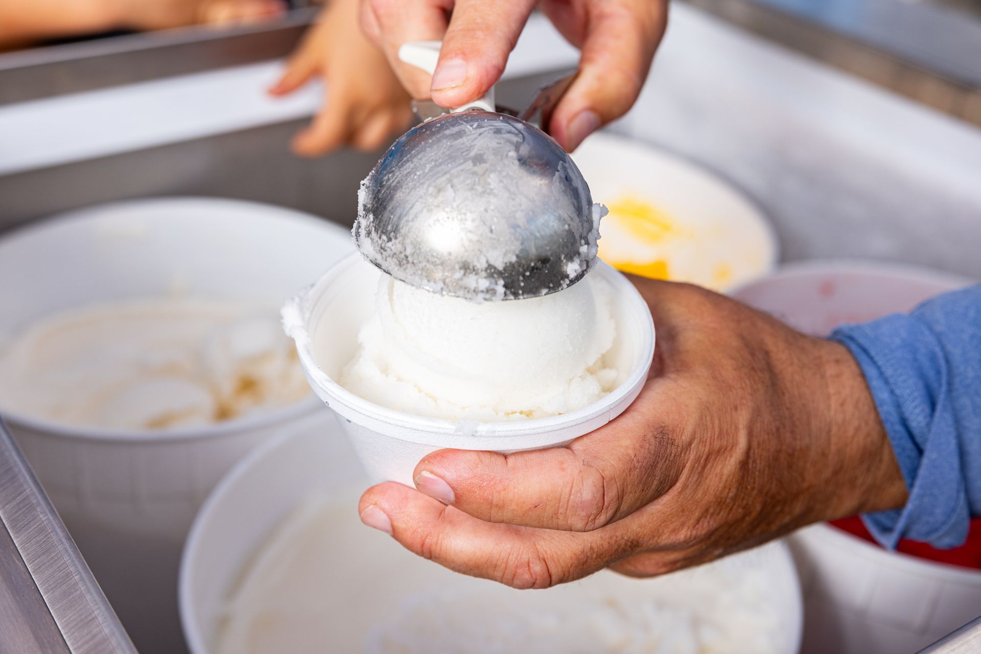 A person is scooping ice cream into a cup.