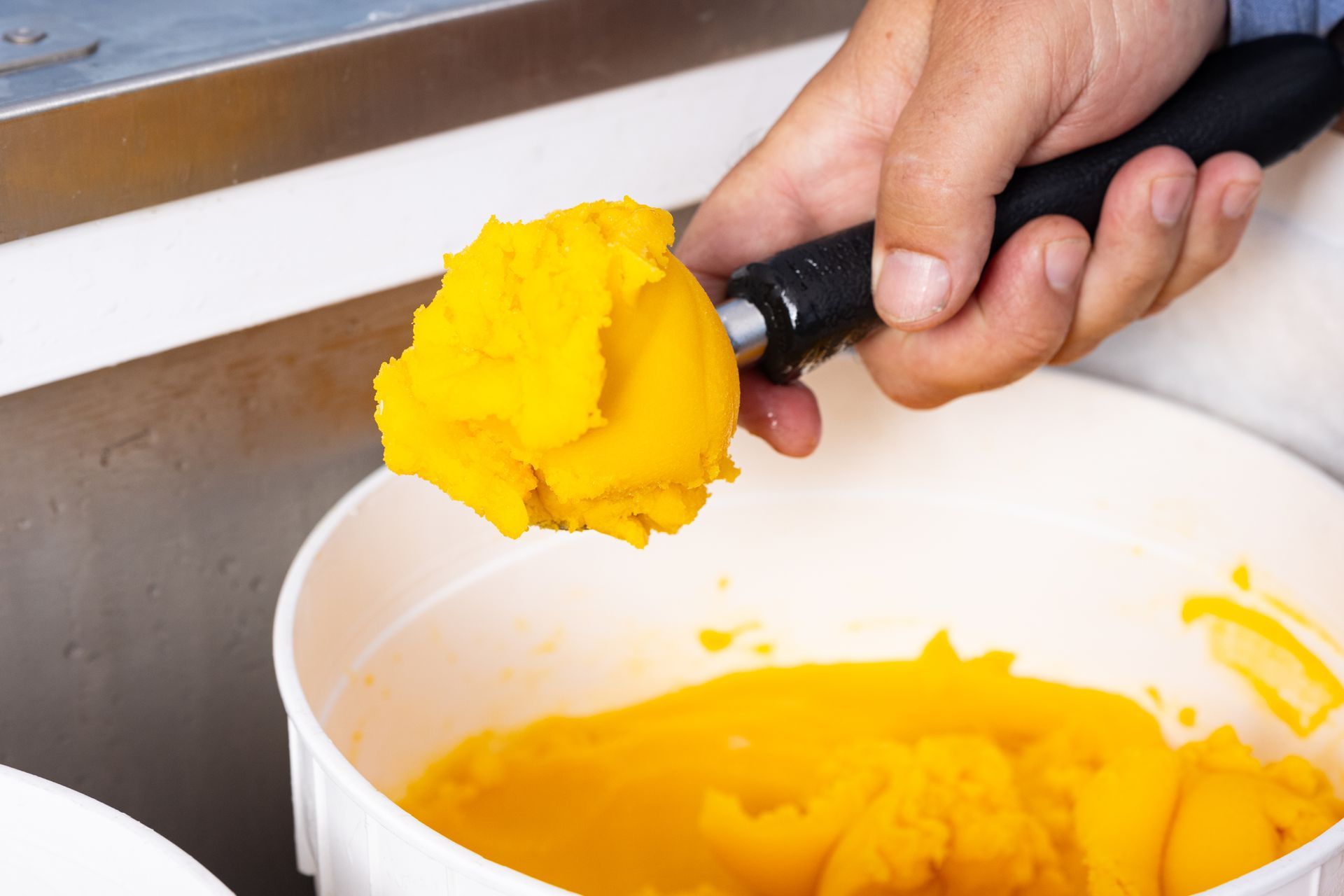 A person is scooping ice cream into a bowl.