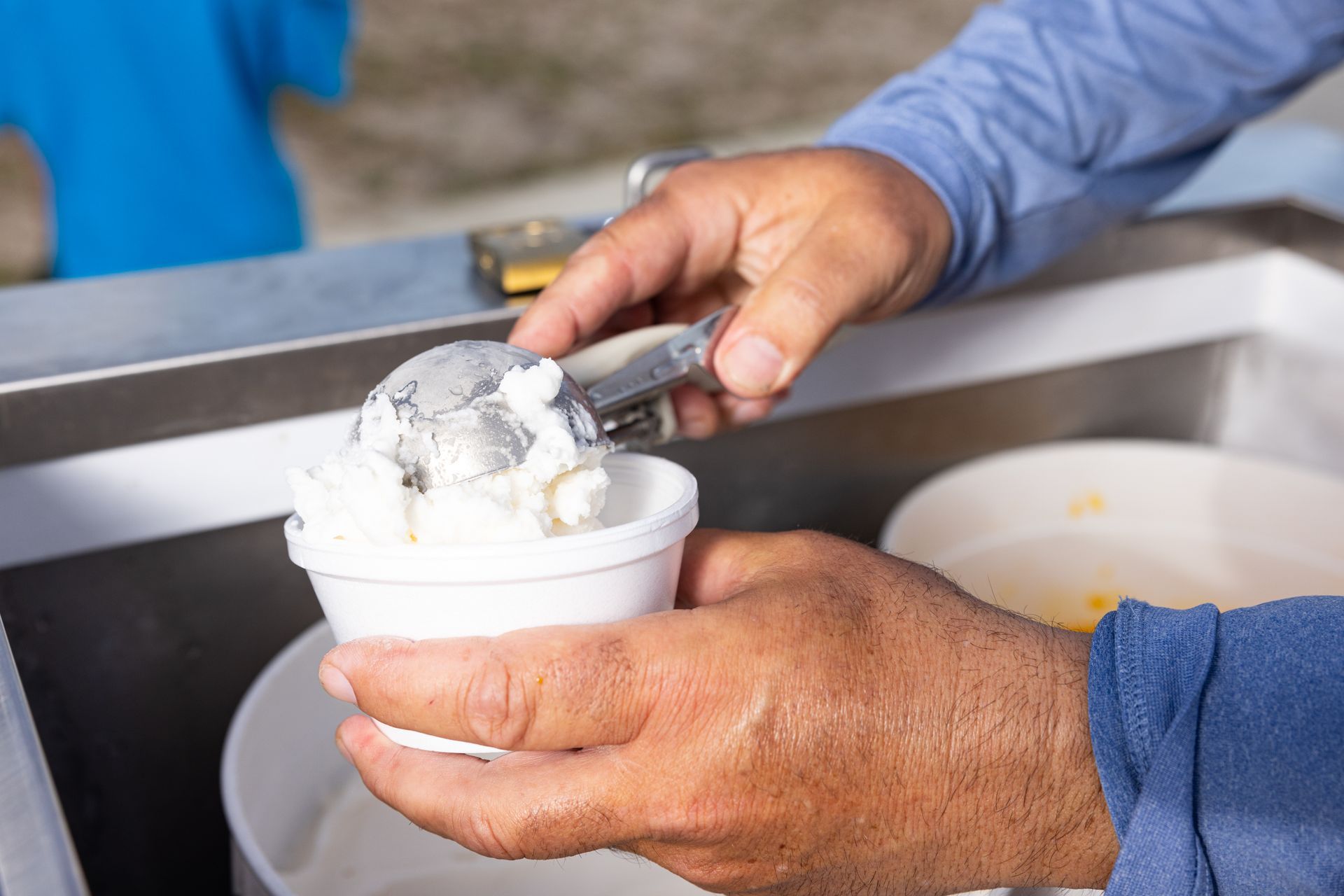 A person is scooping ice cream into a cup.