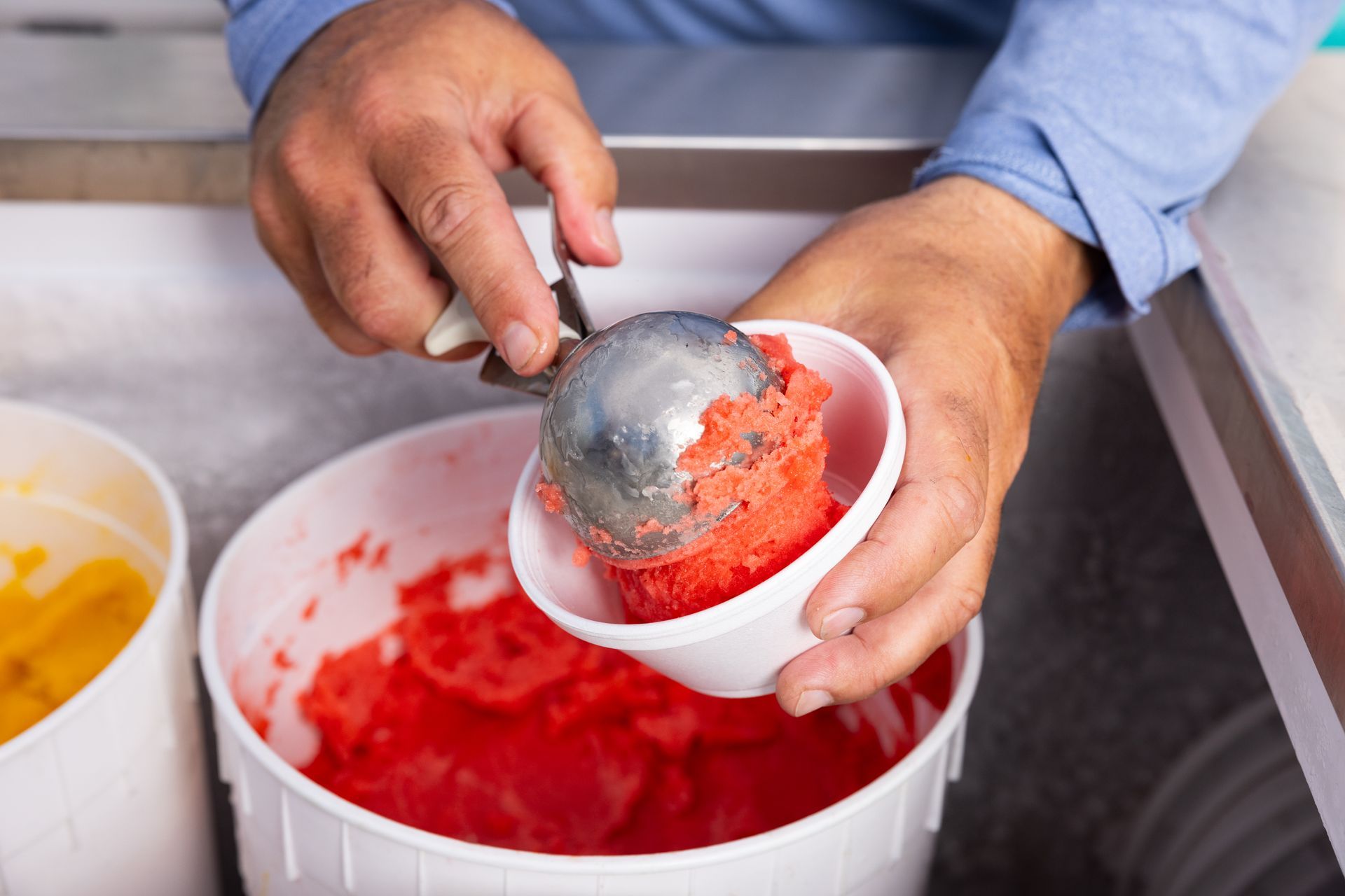 A person is scooping ice cream into a bowl.