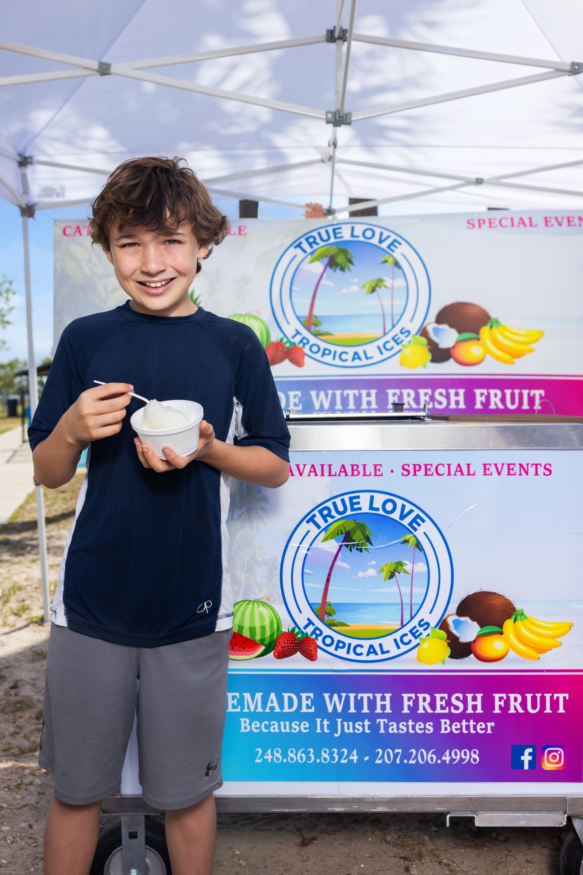 A young boy is eating ice cream in front of an ice cream truck.