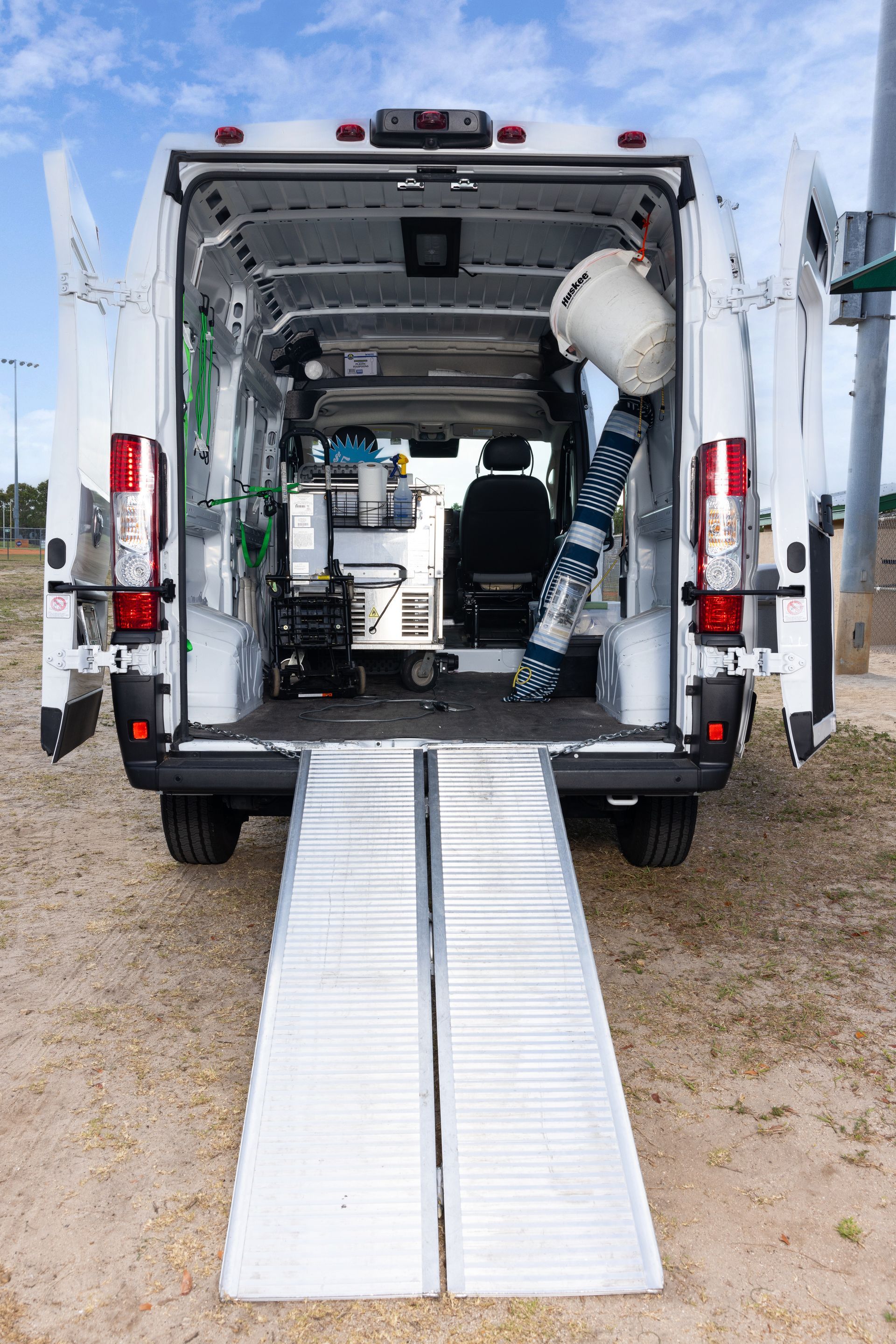 The back of a white van with ramps attached to it.