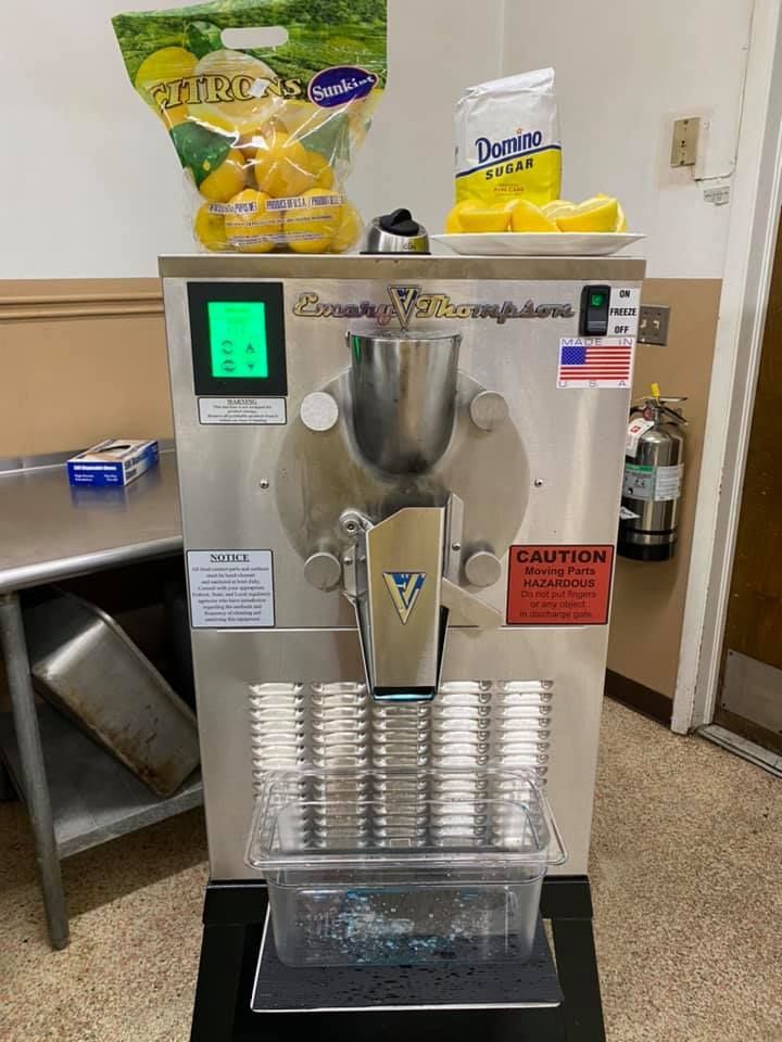 A stainless steel machine is sitting on a table in a kitchen.