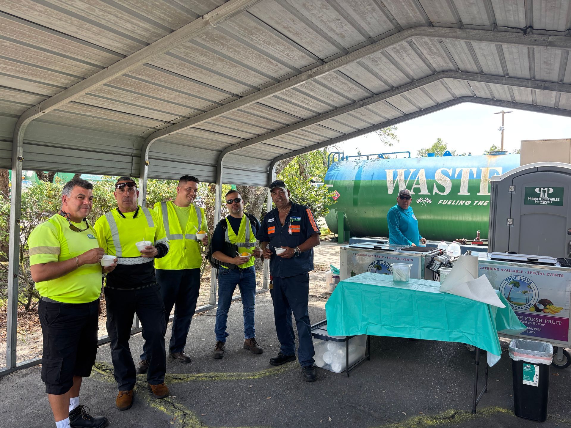Workers in safety vests taking a break under a shelter, a 