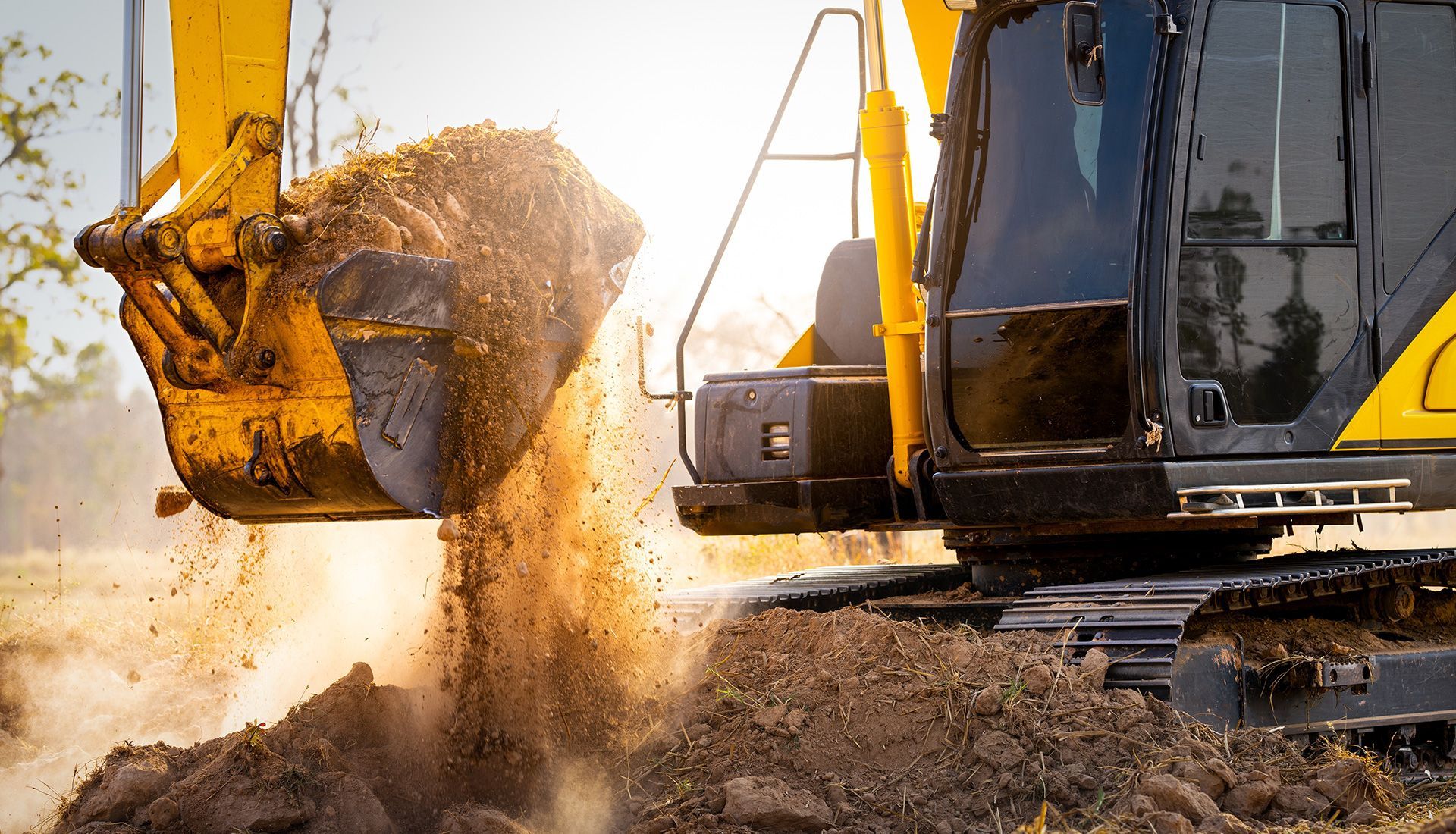 Yellow excavator dumping dirt.