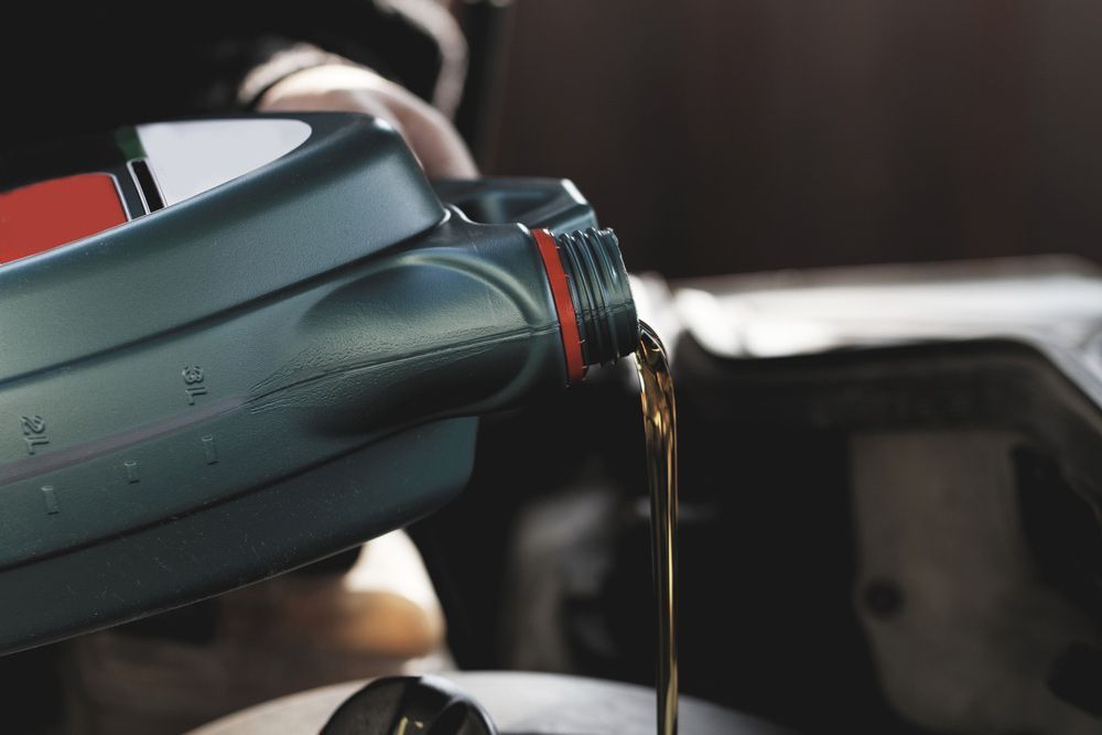 A Person is Pouring Oil Into a Car Engine — Townsville Wholesale Panel & Parts In Garbutt, QLD
