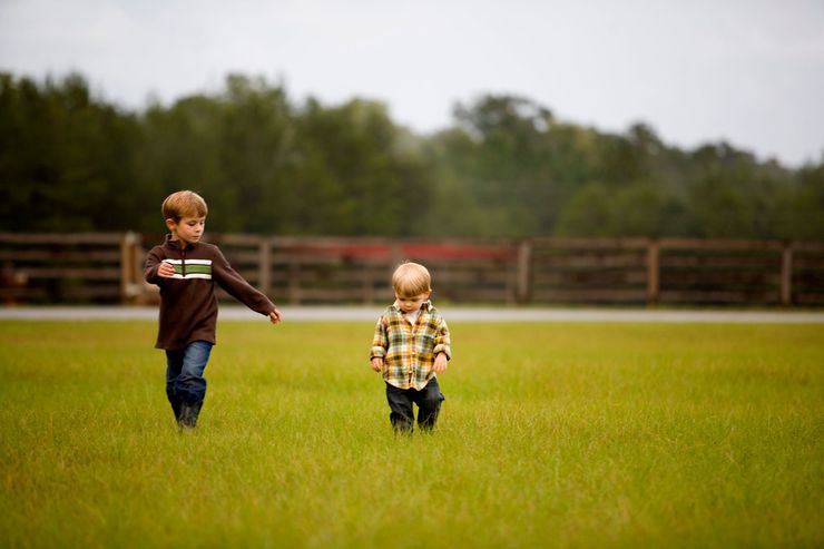 Two little children walking through a field
