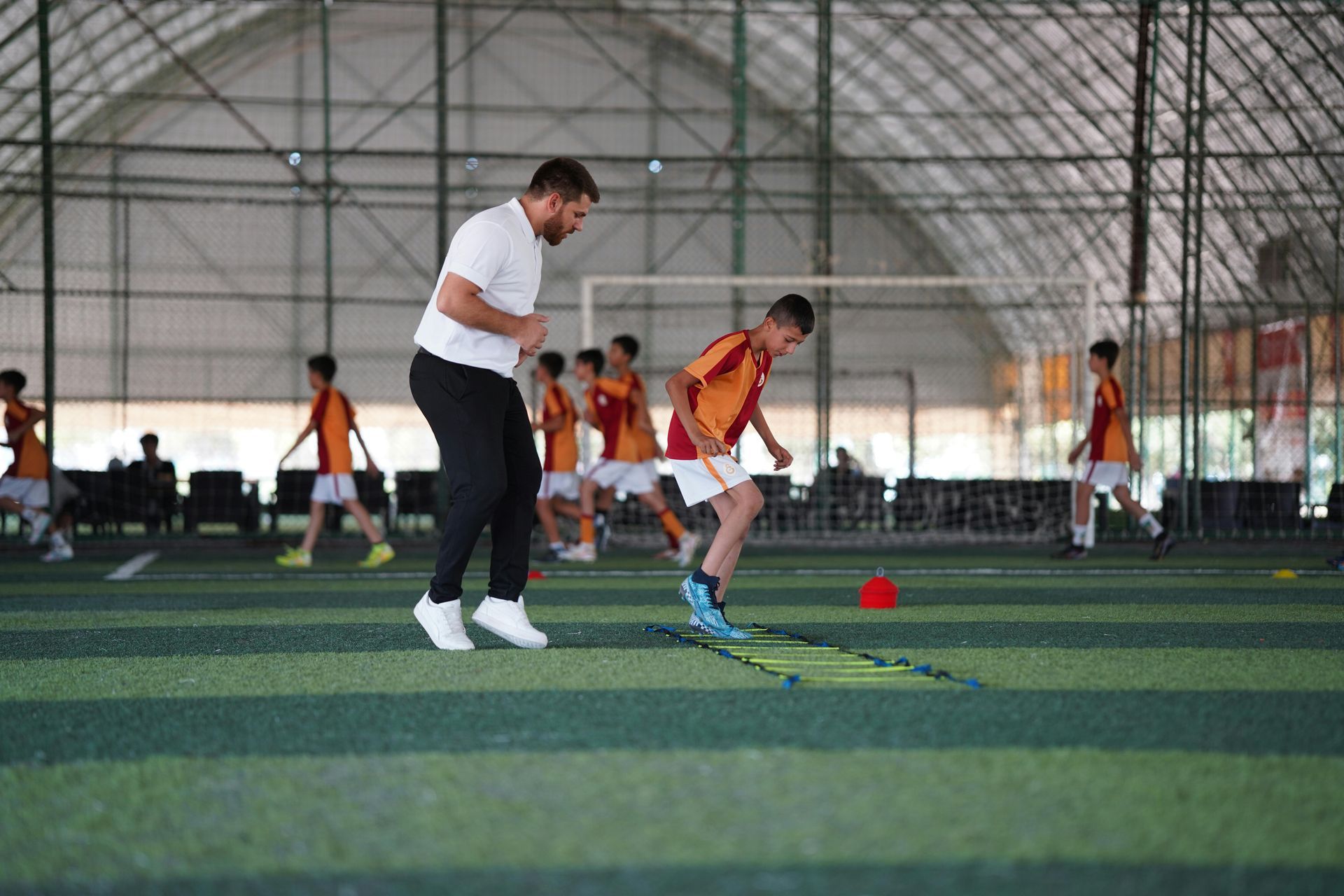 Soccer coach demonstrates a drill for young players on a green field.