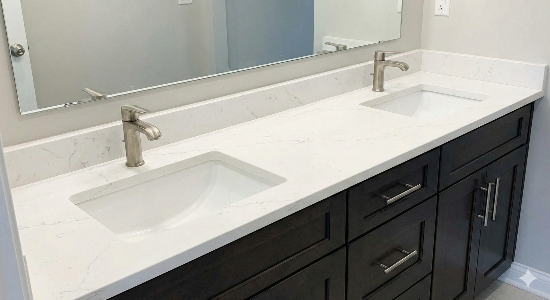 Bathroom vanity with dark cabinets, white countertop, two sinks, and silver faucets.