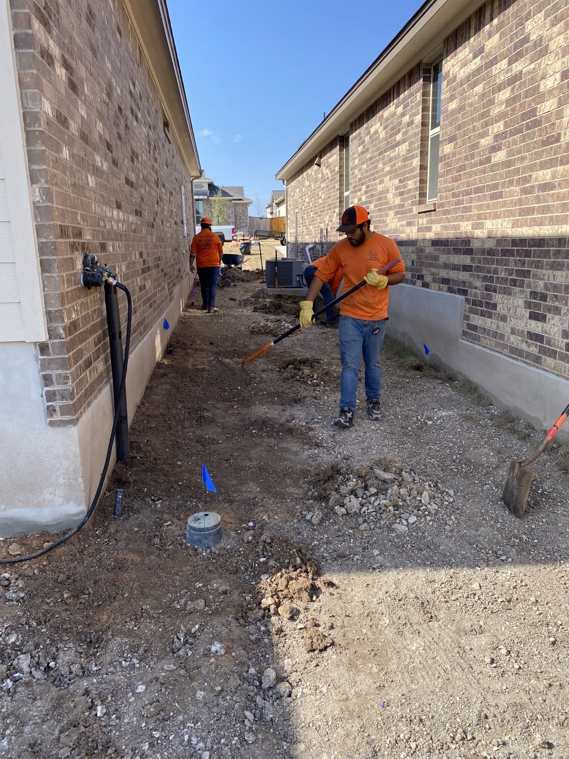 A man is shoveling gravel in front of a brick building.