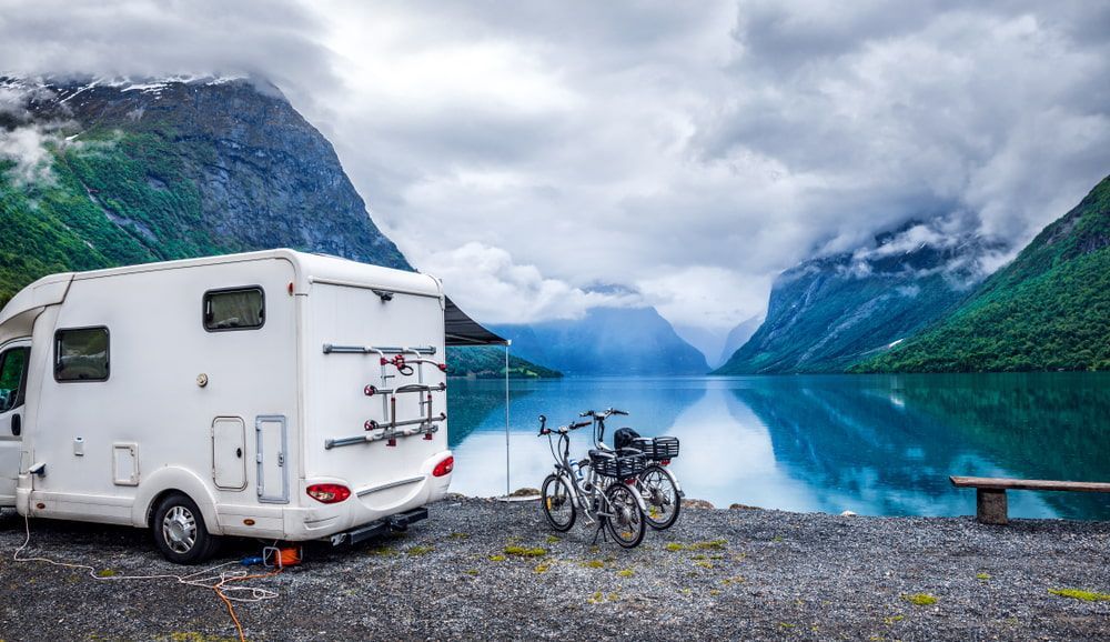 A White Rv Is Parked Next To A Lake With Mountains In The Background — Rainbow Beach Auto Electrics In Rainbow Beach, QLD