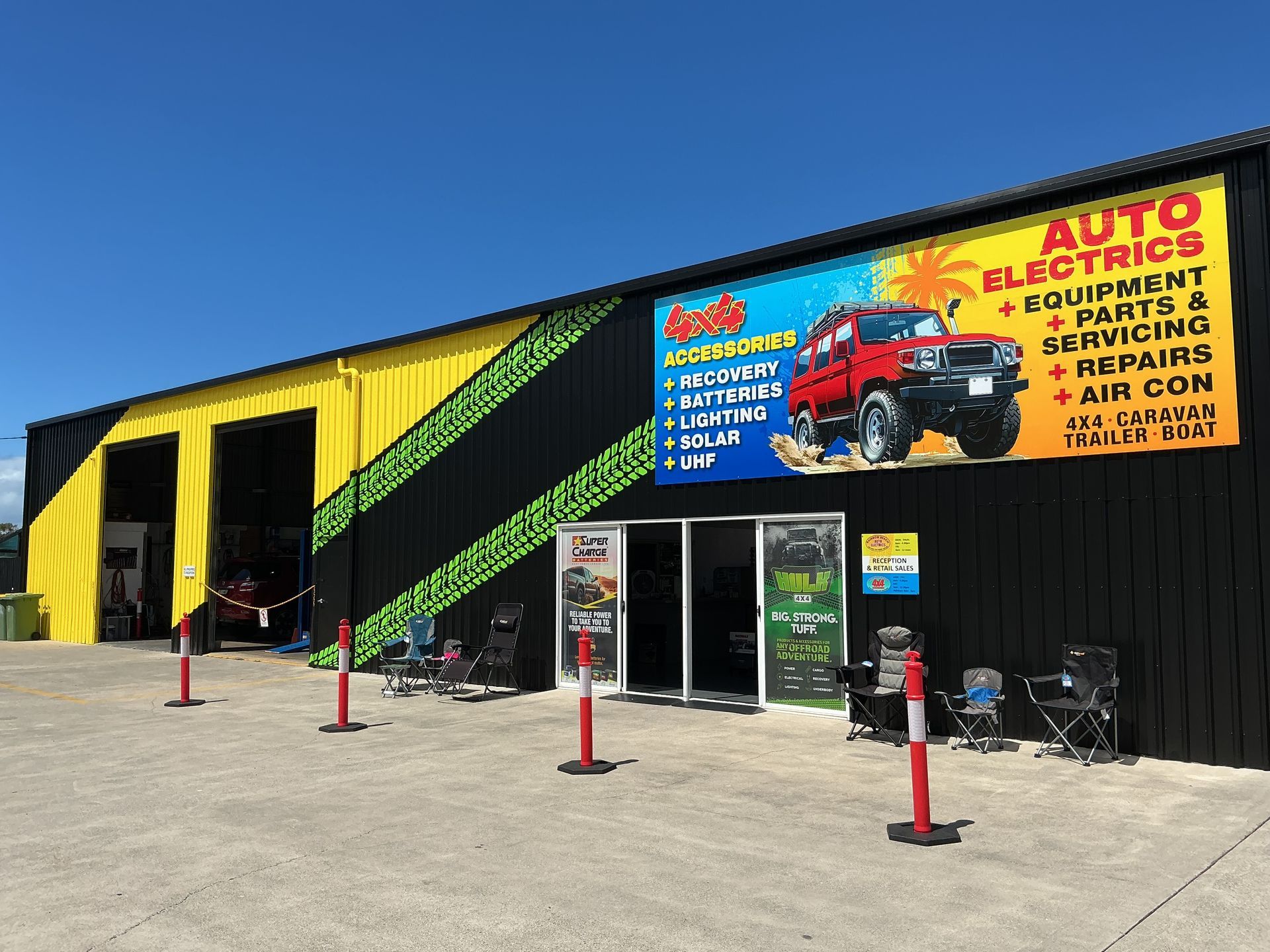 Exterior of an auto electrics shop with yellow and black facade. Signage with a red truck, doors open — Rainbow Beach Auto Electrics In Rainbow Beach, QLD