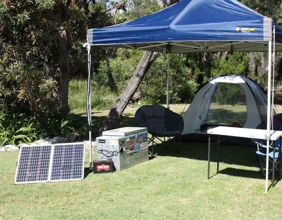 A Tent Is Sitting Under A Blue Canopy Next To A Table And Solar Panels — Rainbow Beach Auto Electrics In Rainbow Beach, QLD