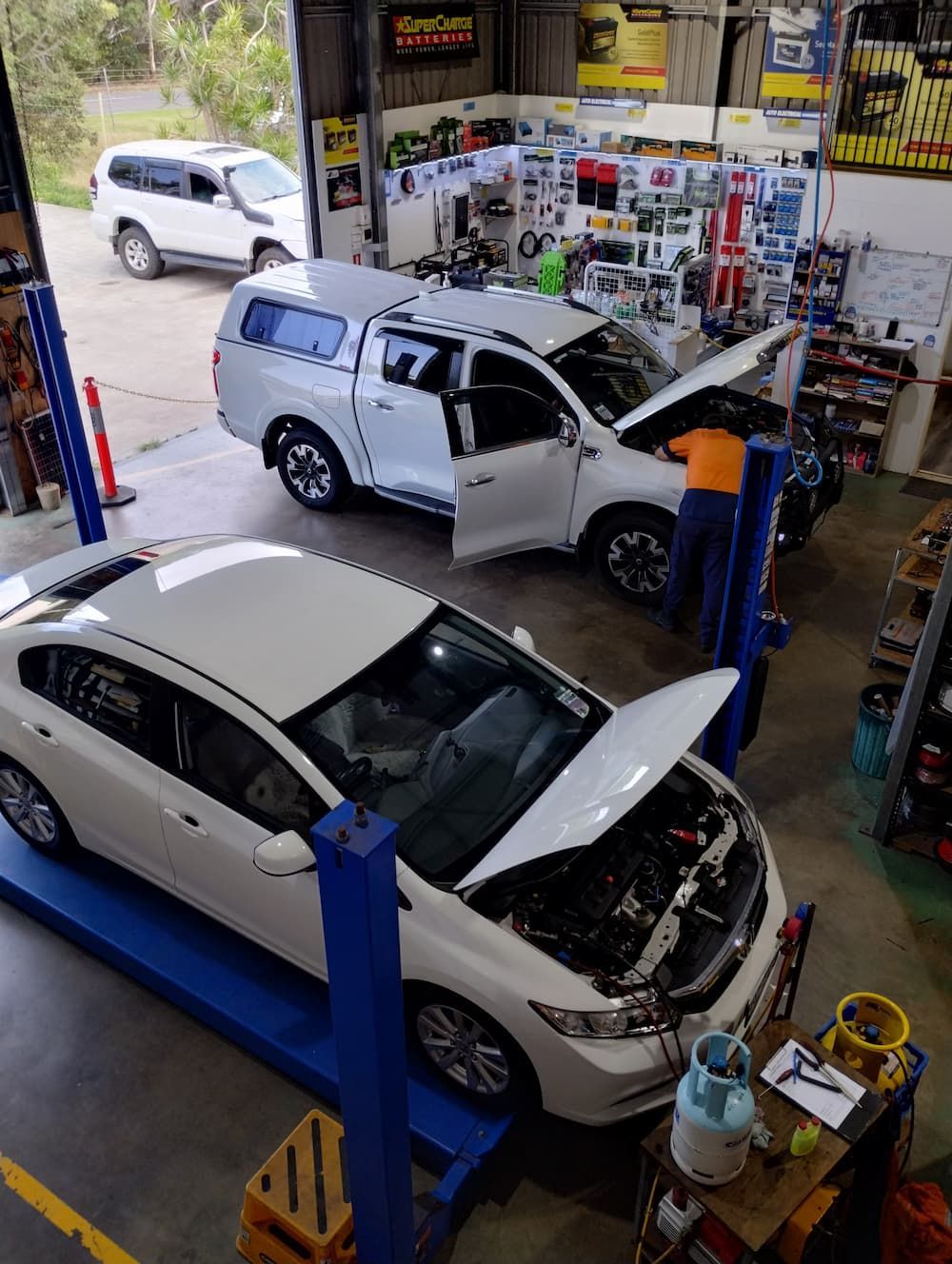 Two White Cars Are Sitting On A Lift In A Garage — Rainbow Beach Auto Electrics In Rainbow Beach, QLD