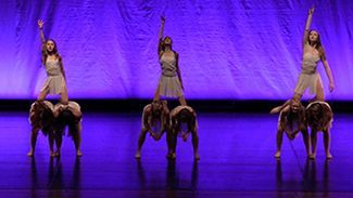 a group of dancers are performing on a stage in front of a purple curtain .