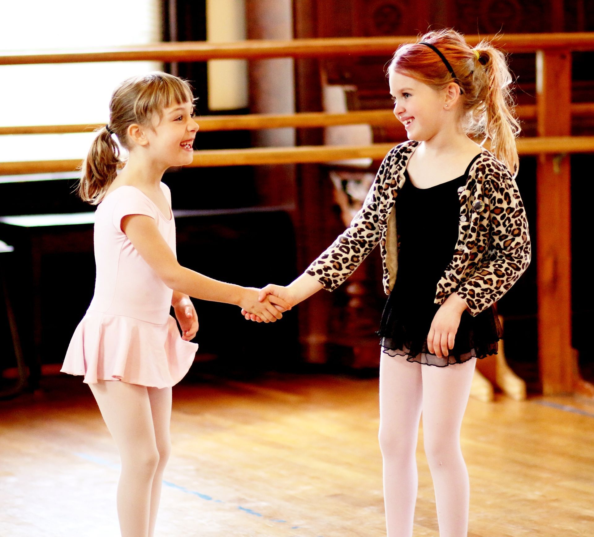two little girls shake hands in a dance studio