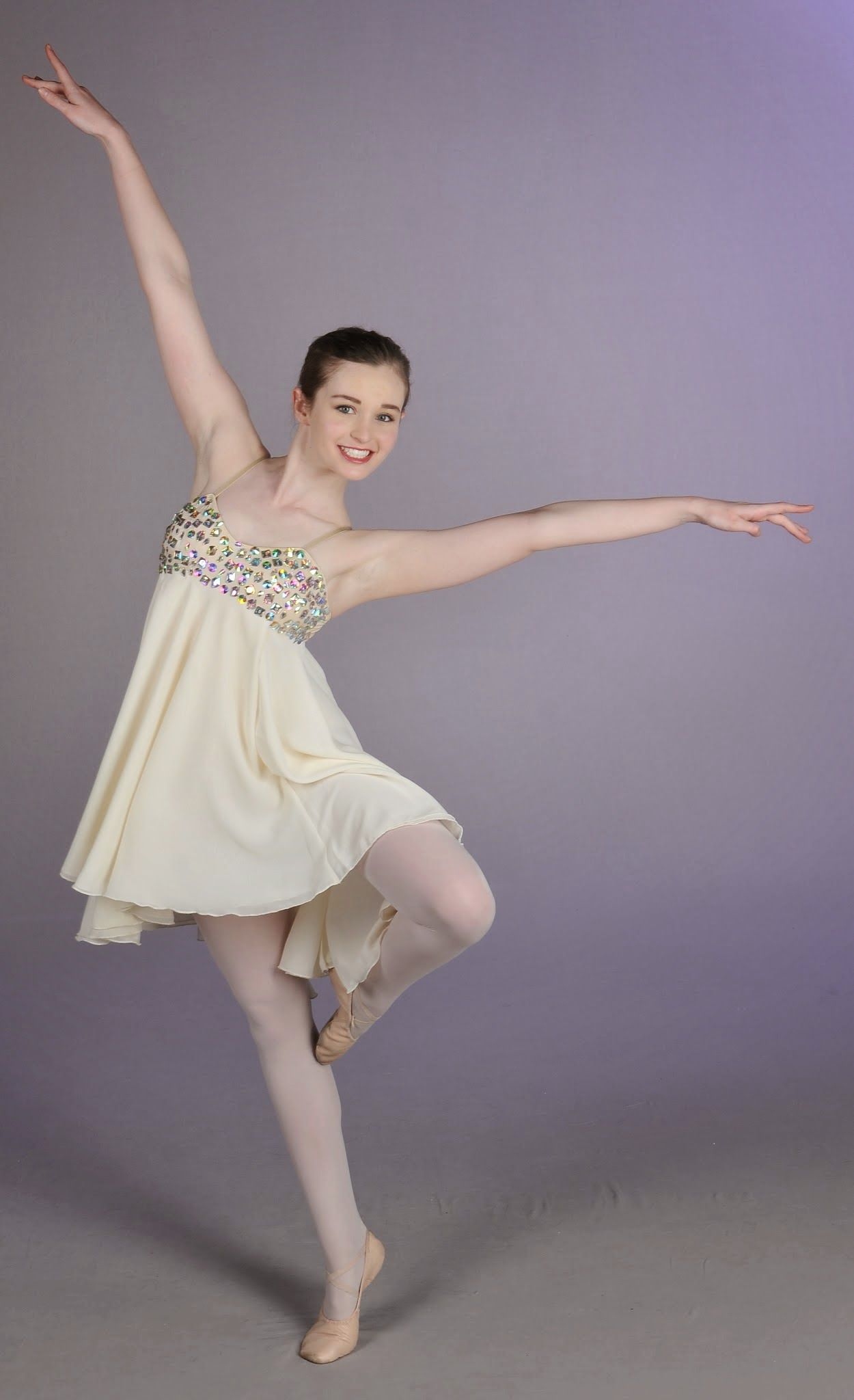 a ballerina in a white dress is standing on one leg .